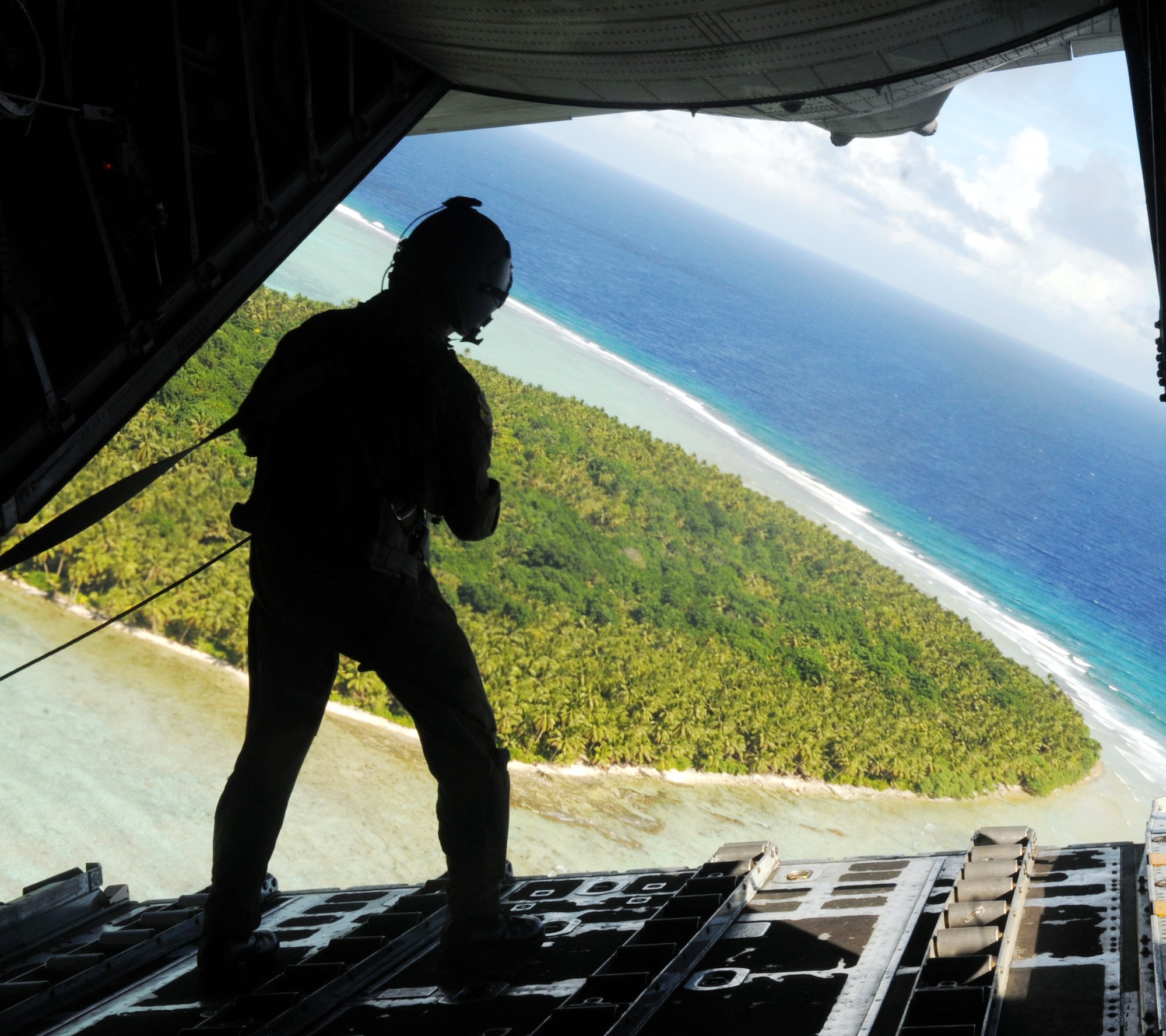 Staff Sgt. Cravenkeo Khamone, a 36th Airlift Squadron loadmaster, spots the drop location for a box of donated goods going to the Chuuk Islands Dec. 16, 2009, in support of Operation Christmas Drop. The operation, which began in 1952, is celebrating its 57th anniversary of helping people. Airmen today continue the tradition delivering supplies to remote islands of the Northern Mariana Islands. (U.S. Air Force photo/Airman 1st Class Julian North)