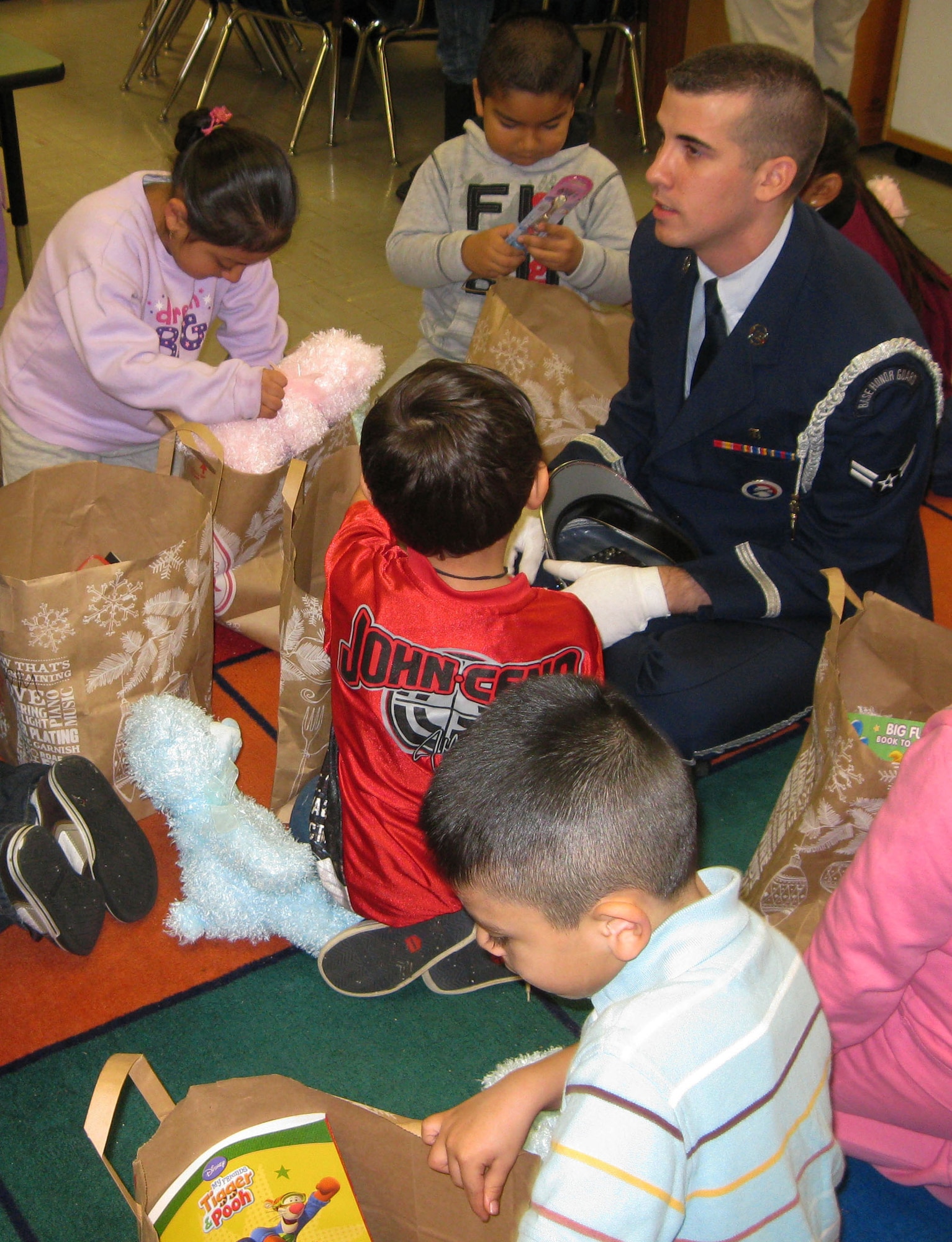 TRAVIS AIR FORCE BASE, Calif. -- A reservist assigned to the 349th Air Mobility Wing Honor Guard visits with  kindergarten children at Anna Kyle Elementary School Dec. 14. Each year, for more than 25 years, the reservists from the 349th Air Mobility Wing have brought joy to local kindergarteners through Operation Teddy Bear. This community outreach project gathers and delivers teddy bears and gift bags to disadvantaged kindergarten children in local Title 1 schools. Sponsored by the wing Top Three Group, different squadrons each year share in the preparations and do the bulk of the work. This year, the 349th Medical Group was the lead unit. The 349th AMW Honor Guard also participates in the Operation Teddy Bear visits.  (U.S. Air Force photo/Senior Master Sgt. Ellen L. Hatfield).     