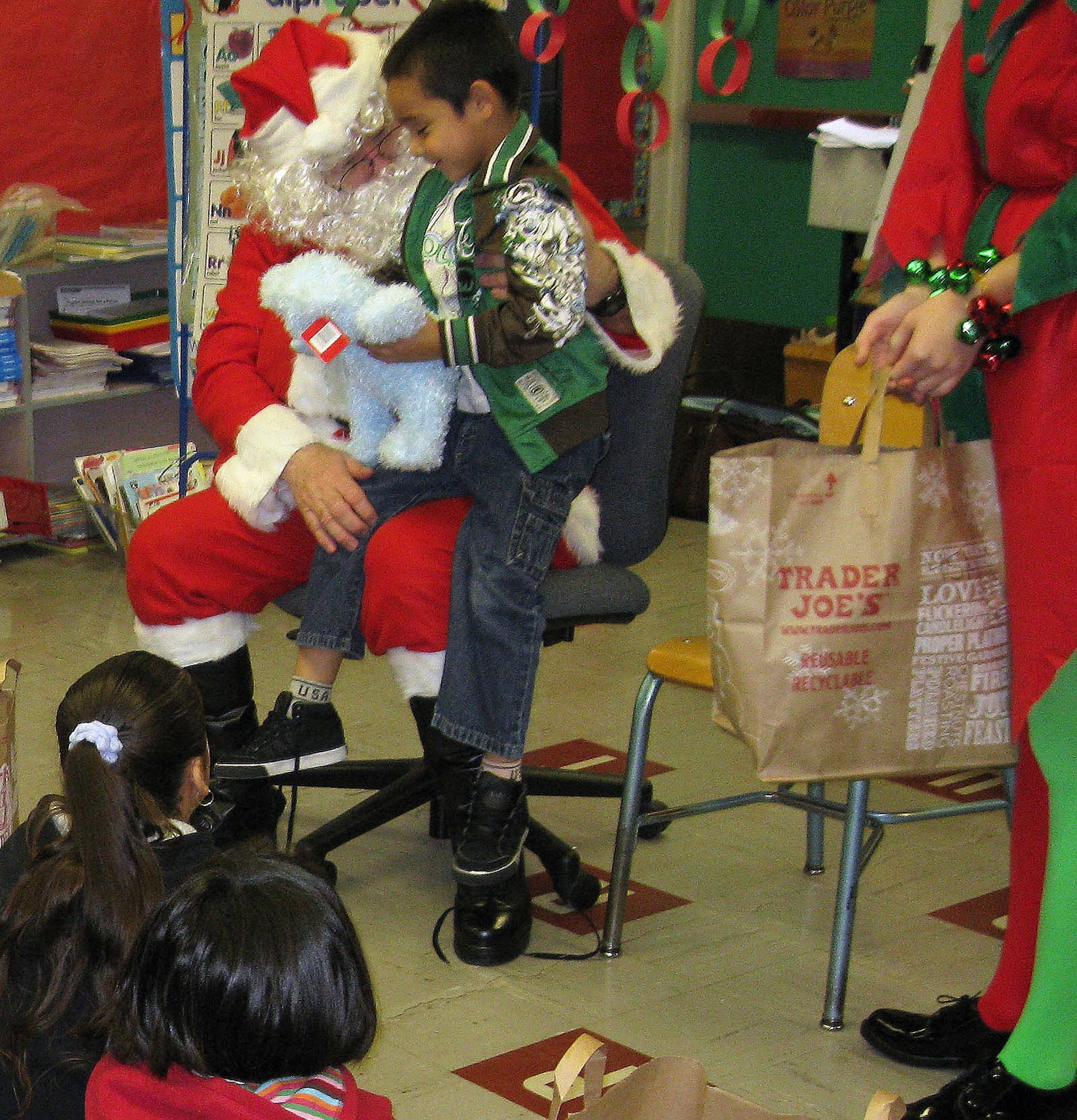 TRAVIS AIR FORCE BASE, Calif. -- Santa Claus (played by Technical Sgt. Dan Allen, 349th Medical Squadron), listens to the Christmas wish of a kindergarten child at Anna Kyle Elementary School Dec. 14. Each year, for more than 25 years, the reservists from the 349th Air Mobility Wing have brought joy to local kindergarteners through Operation Teddy Bear. This community outreach project gathers and delivers teddy bears and gift bags to disadvantaged kindergarten children in local Title 1 schools. Sponsored by the wing Top Three Group, different squadrons each year share in the preparations and do the bulk of the work. This year, the 349th Medical Group was the lead unit. The 349th AMW Honor Guard also participates in the Operation Teddy Bear visits. (U.S. Air Force photo/Senior Master Sgt. Ellen L Hatfield).     