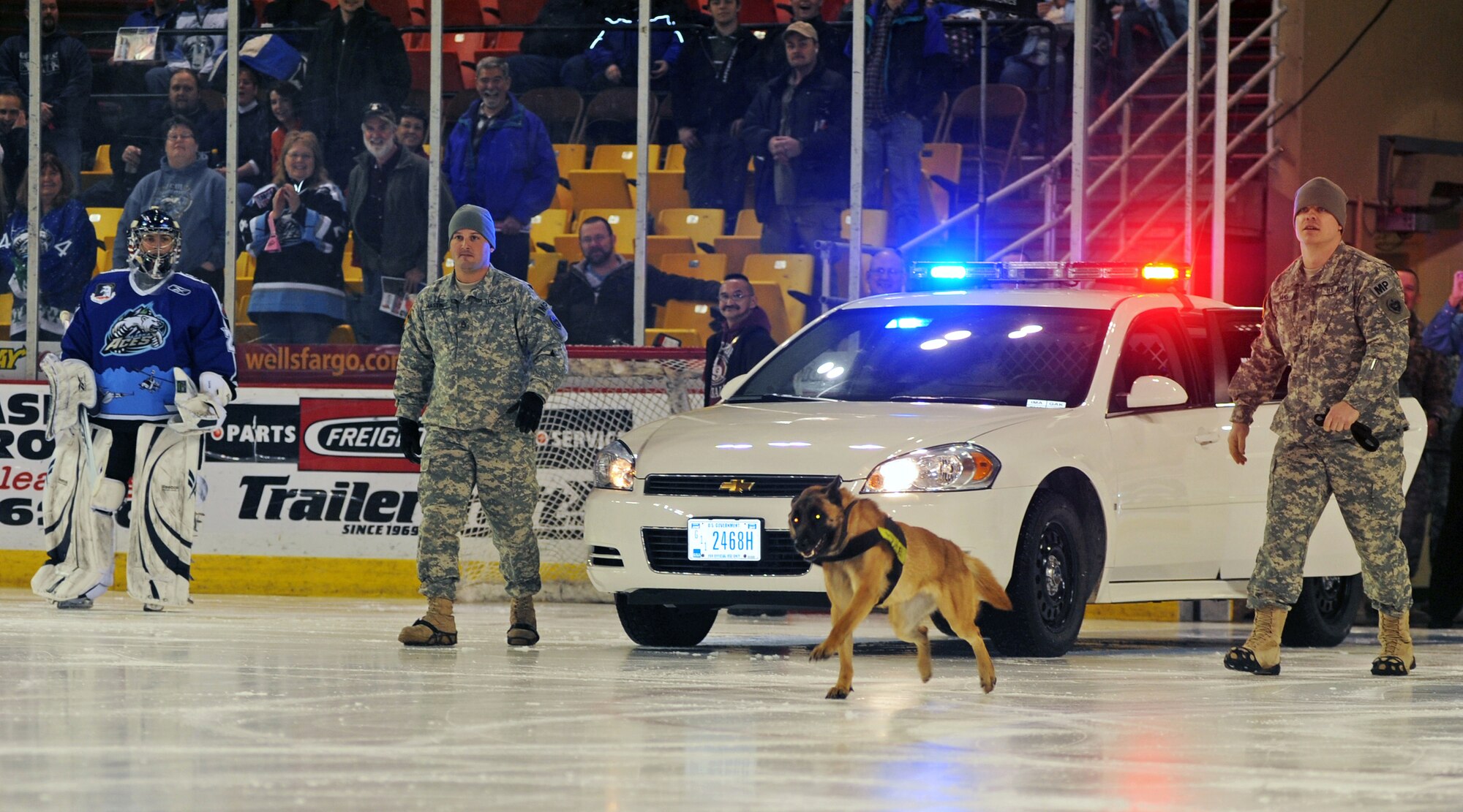 ANCHORAGE, Alaska -- Military police and a military working dog chase down a person that held the ceremonial puck hostage Dec. 11. The Alaska Aces organization held a three-game military appreciation series Dec. 11-13. (U.S. Air Force photo/Senior Airman Laura Turner)
