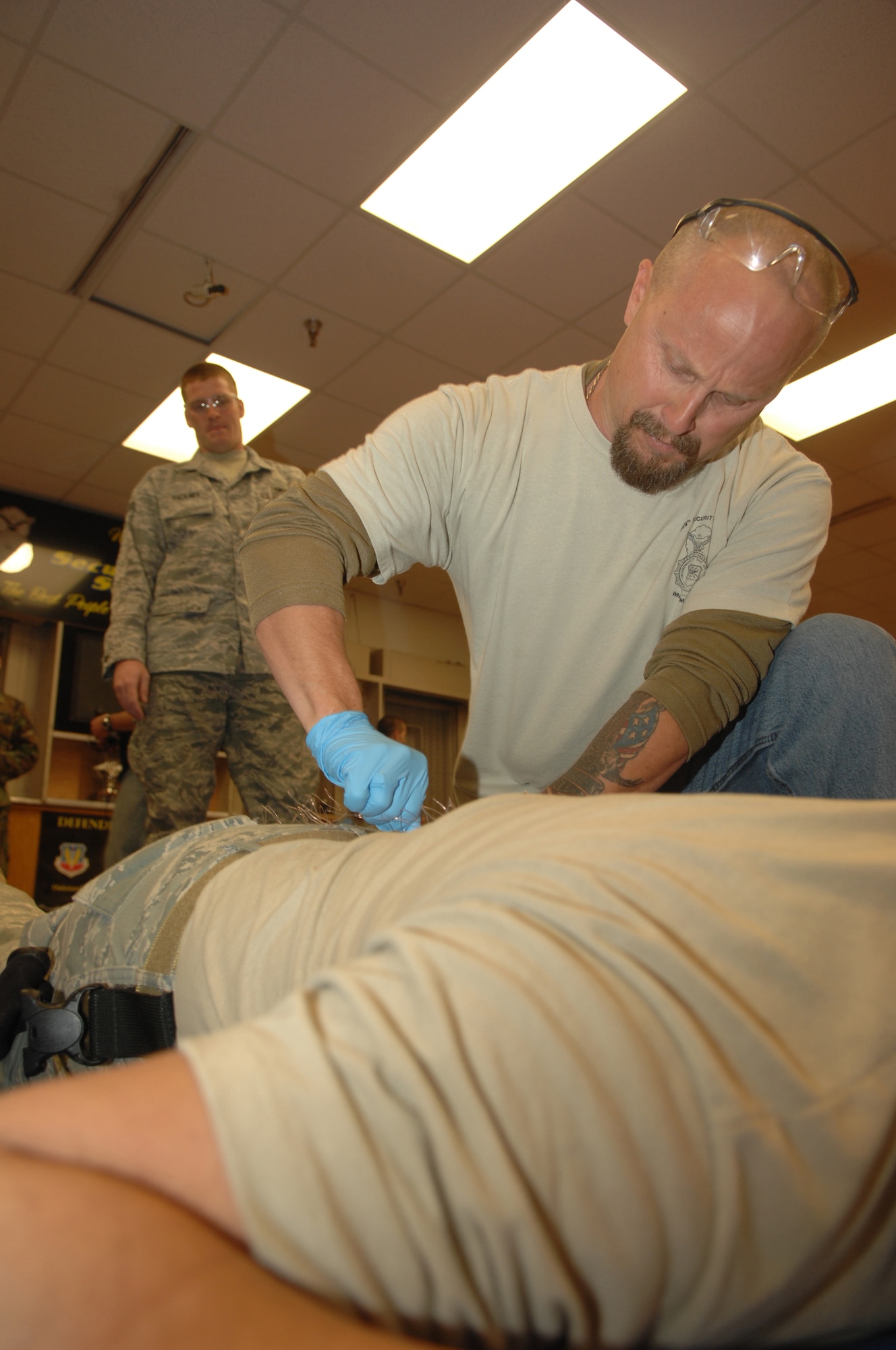Tommy Hutfles, 509th Security Forces Squadron instructor, removes probes from a security forces member's back that were fired from a taser during the Field Training Officer course, here Dec. 17, 2009.  The instructors took volunteers to demonstrate to them exactly what happens when a taser or stun gun is used.  (U.S. Air Force photo/Senior Airman Jessica Snow)