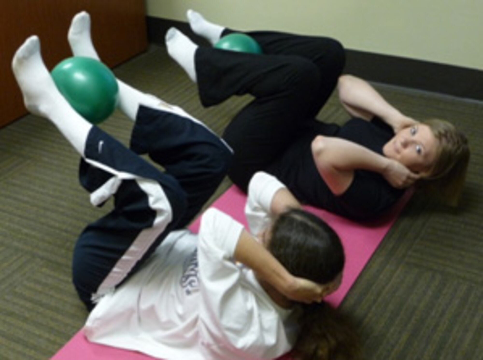 Master Sgt. Lucia Wilson and Tech. Sgt. Melissa Parker, both from the 315th Aerospace Medicine Squadron, complete “above & beyond” crunches one recent morning at Charleston Air Force Base, S.C. (U.S. Air Force photo/Col. Christopher Lentz)