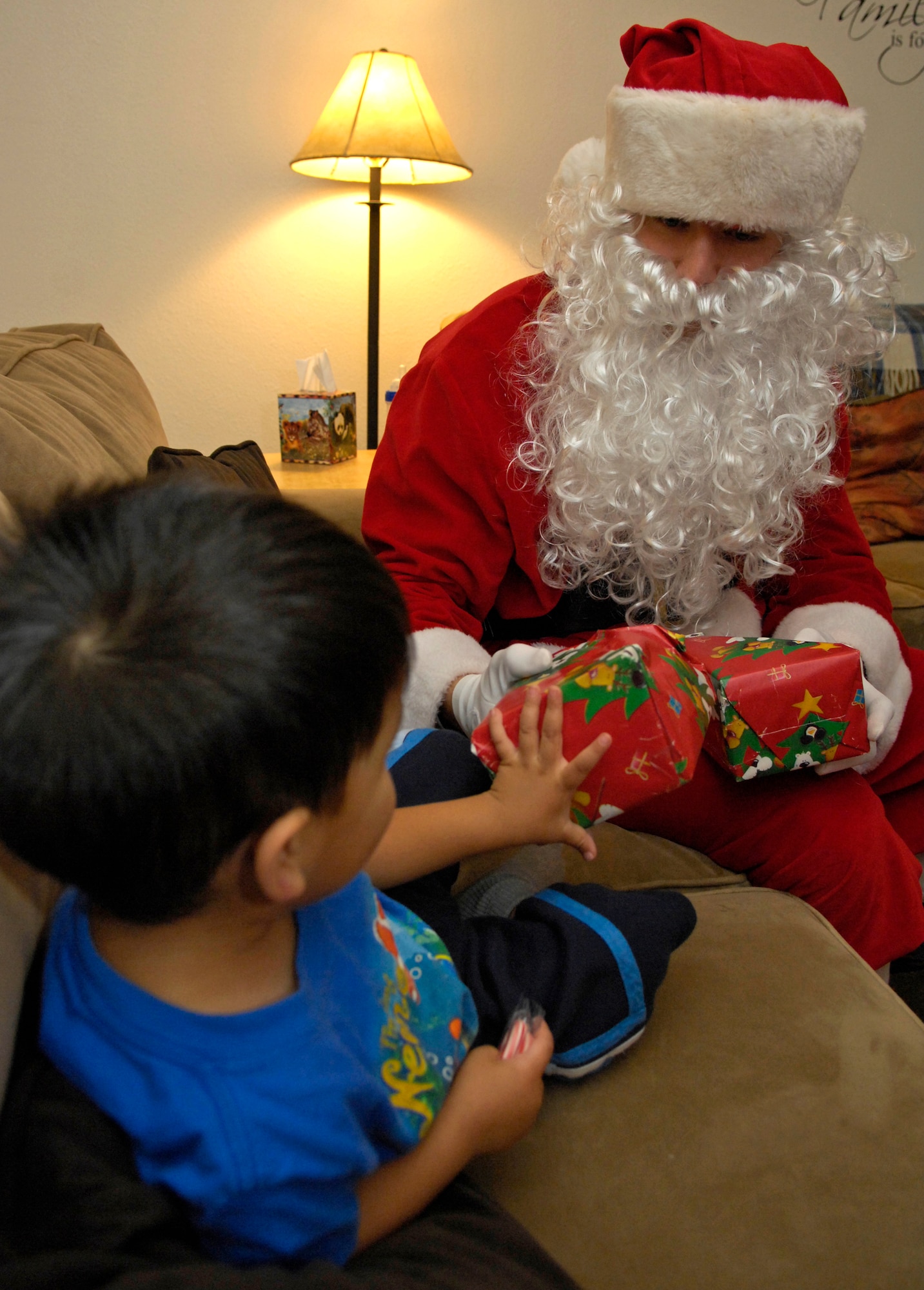 VANDENBERG AIR FORCE BASE, Calif. --  Starting off Christmas early, Santa hands Tristan Anzara, son of Tech Sgt. Nancy Anzara, from the 533rd Training Squadron, an early Christmas present to open here Wednesday, Dec. 15, 2009. The Santa visits were planned with the parents of each household to come and surprise the kids of the house with early Christmas presents provided by the parents.  (U.S. Air Force photo/Airman 1st Class Andrew Lee) 