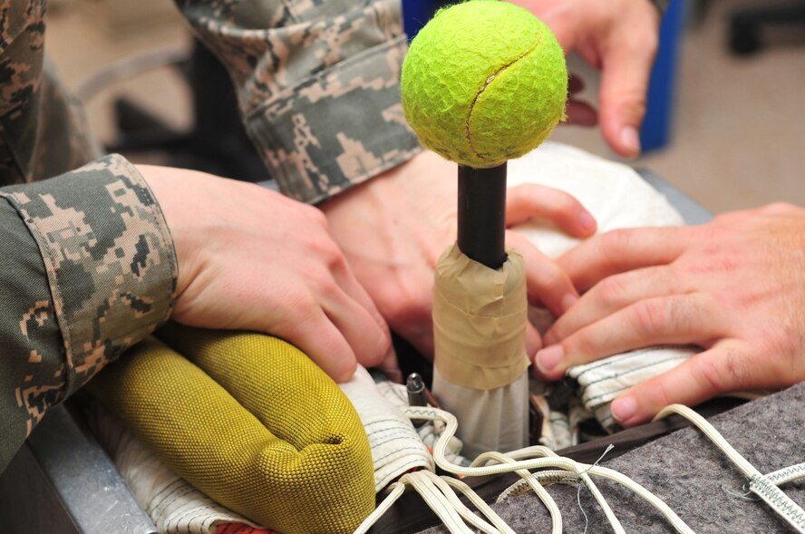 Airmen from the 4th Operations Support Squadron life support flight pack the last bit of canopy into the holding canister on Seymour Johnson Air Force Base, N.C., Dec. 15, 2009. A tennis ball protects the mortar, an explosive device that launches the parachute, from dirt and debris and keeps the canopy from being ripped. (U.S. Air Force photo/Airman 1st Class Rae Perry)