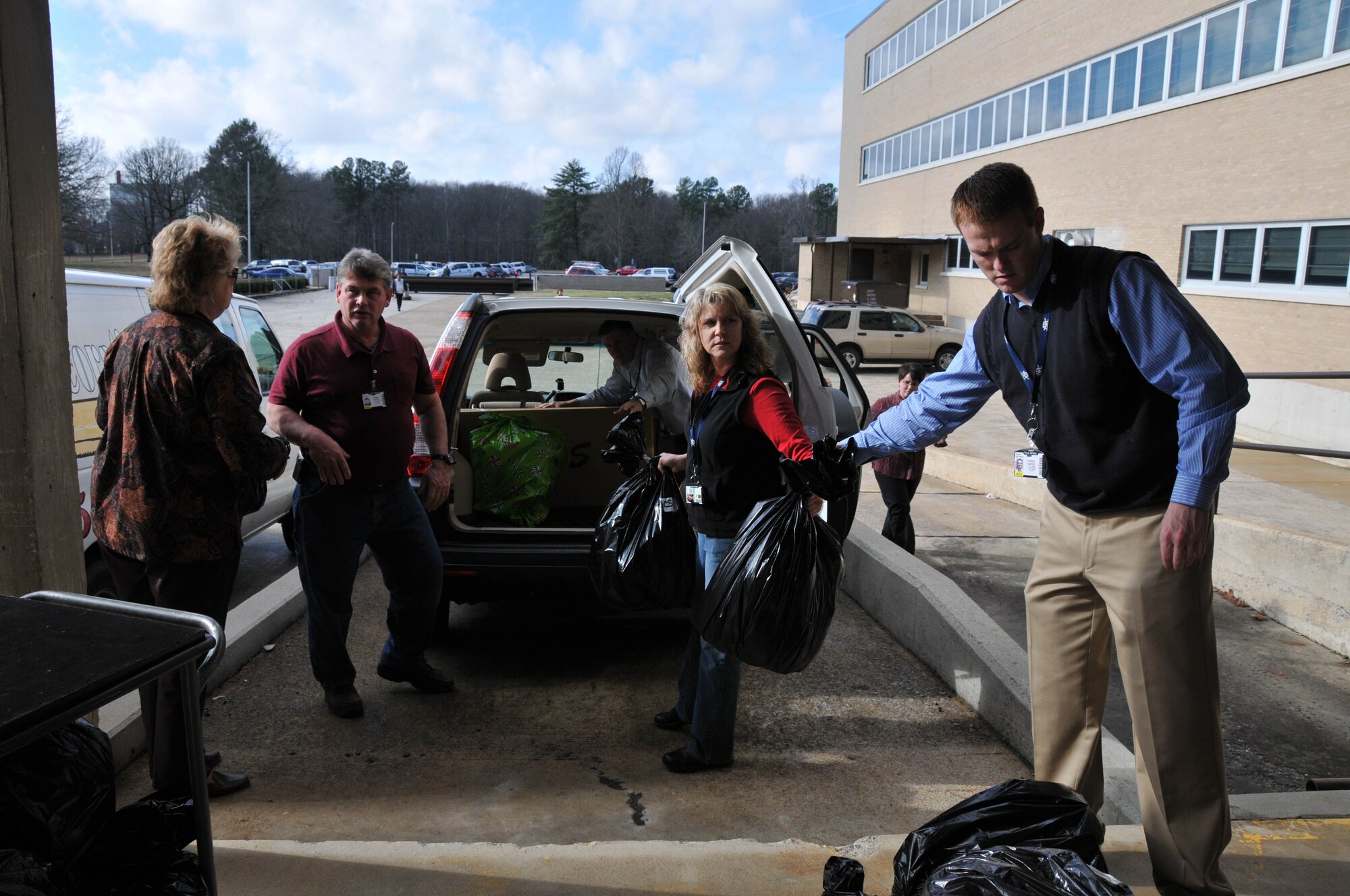 Centerstone Mental Health case worker Carrie Hawk (left) helps Aerospace Testing Alliance employees Warner Tombs, Suzanne Luthi and Fred Hutchinson load Christmas gifts into a van. (Photo by Gary Johnson)