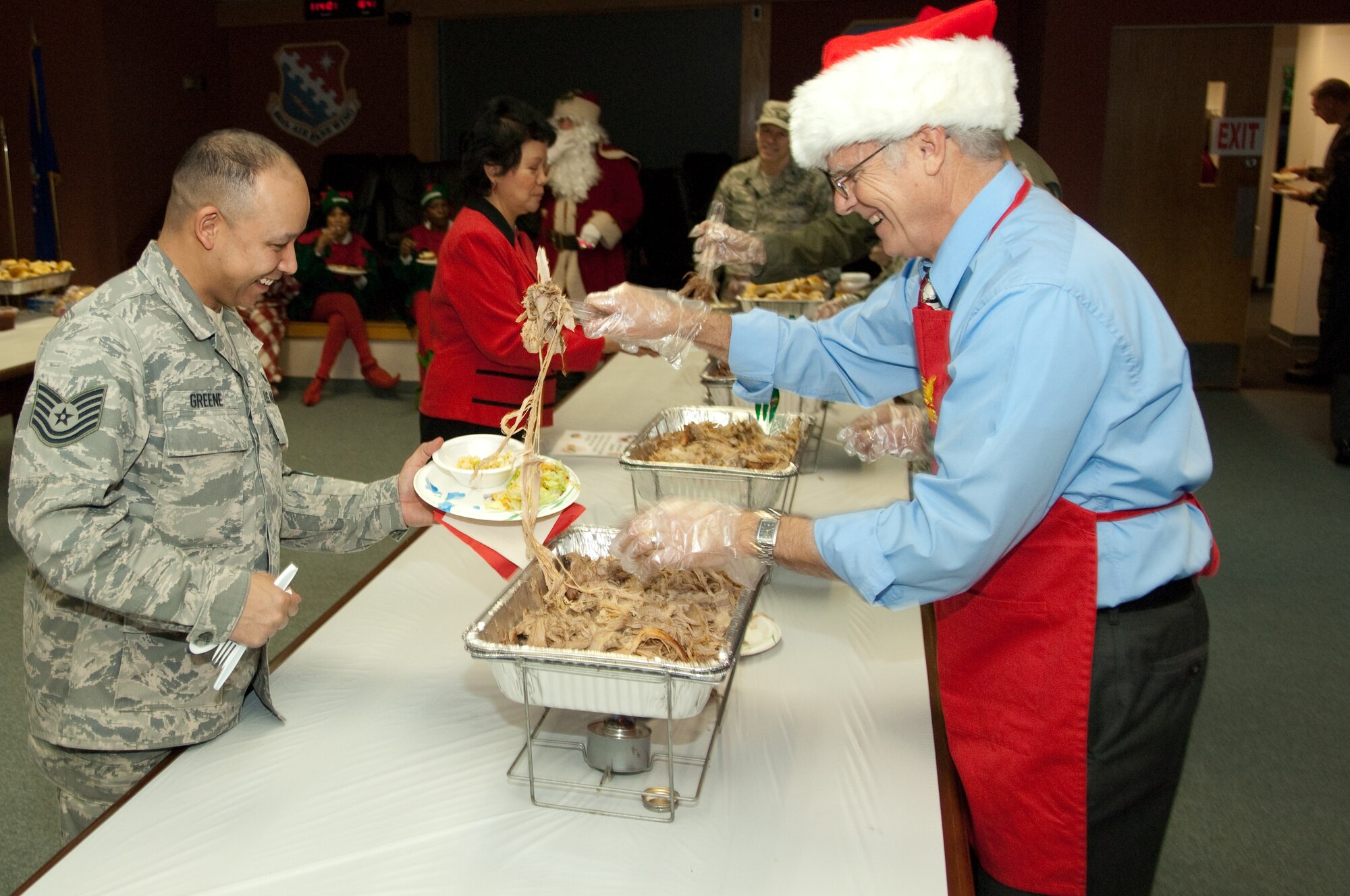 HANSCOM AIR FORCE BASE, Mass. -- Chuck Denmark (right), 66th Air Base Wing plans and programs director, serves smoked pork to Tech. Sgt. Jamil Greene, 66 ABW plans and programs, during the 66 ABW Holiday Party. 66 ABW members from across the base gathered in the Brown Building Dec. 10 to enjoy live holiday music, food, desserts and raffle prizes. (U.S. Air Force Photo by Rick Berry)