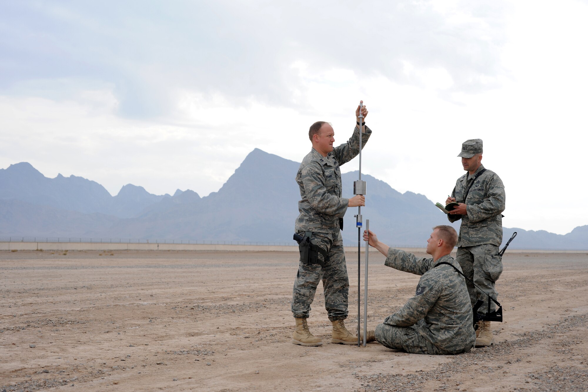 Surrounded by the mountains in western Afghanistan, U.S. Air Force Capt. Luke Stumme uses a dynamic cone penetrometer (DCP) to measure the soil subsurface strength of the airfield at Forward Operating Base (FOB) Farah, Dec. 2, 2009. While Capt. Stumme systematically lifts and drops a 17 pound weight on the penetrometer rod, Tech. Sgt. Joel Bane gauges the distance the rod is travelling into the dirt, while Capt. Jay Michaels records how many hits it takes for the rod to travel each marked distance. Capts. Stumme and Michaels along with Sergeant Bane are all members of an Air Force Airfield Assessment team that is deployed in Afghanistan to analyze data from visits to all established airfields with a major military presence. The results of their study will be briefed to the International Security Assistance Force (ISAF) commander. The ultimate goal of the team is to help find solutions for getting more forces into the war zone and sustaining those forces.
