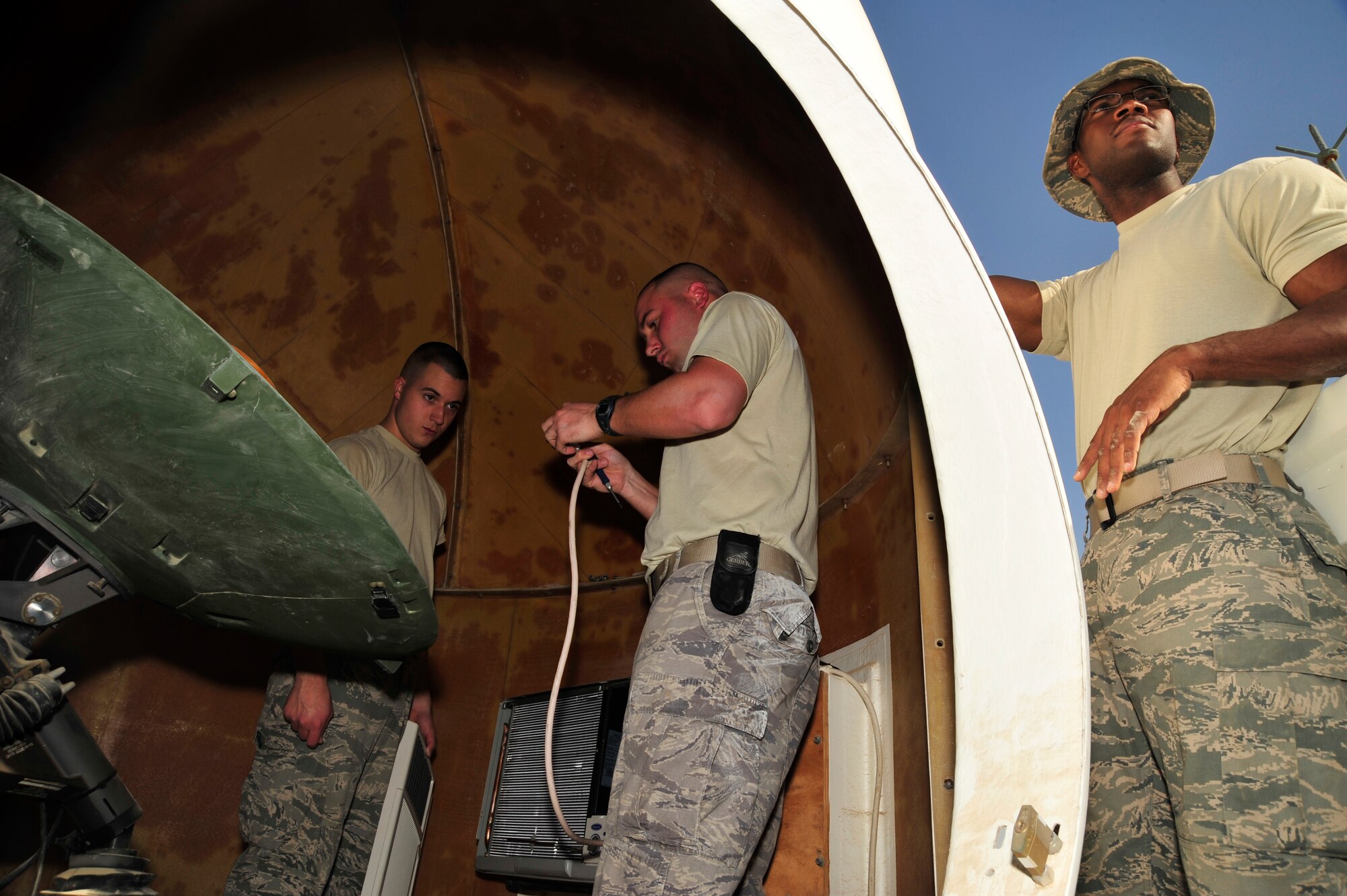 SOUTHWEST ASIA - Staff Sgt. Derek Rhudy, Airman 1st Class Matthew Ventresca and Senior Airman Oliver Abraham, members of  the 380th Expeditionary Civil Engineer Squadron, install a replacement air conditioner unit on the roof of a Communications Squadron building Dec. 17, 2009. Sergeant Rhudy is deployed from Scott Air Force Base, Ill., and grew up in Plainfield, Ind. Airman Ventresca is deployed from McGuire Air Force Base, N.J. and grew up in Philadelphia. Airman Abraham is deployed from Pope Air Force, N.C. and grew up in St. Thomas, U.S. Virgin Islands. (U.S. Air Force photo/Tech. Sgt. Charles Larkin Sr)