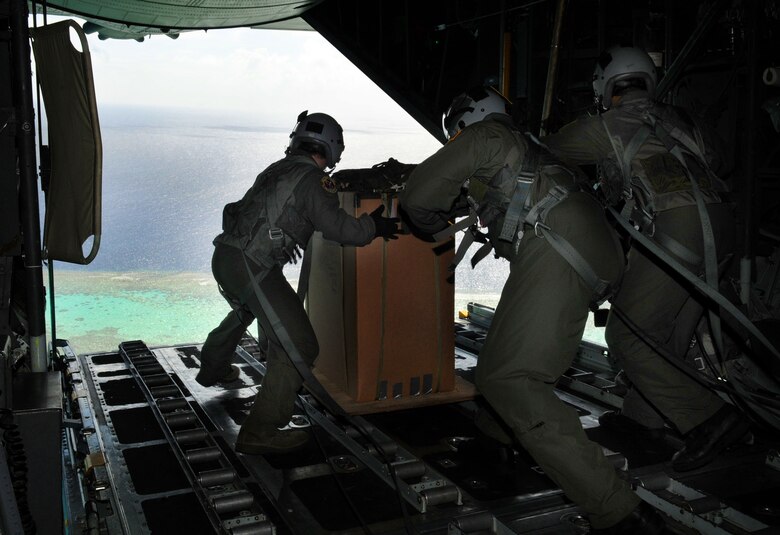 ANDERSEN AIR FORCE BASE, Guam - Airman from the 36th Airlift Squadron, Yokota Air Base, Japan, prepare to drop a package over a remote island near Chuuk Dec. 17. Operation Christmas Drop is a non-profit organization powered by volunteers from Andersen Air Force Base and the local Guam community. Each year, the two join forces to aid over 30,000 islanders in Chuuk, Palau, Yap, Marshall Islands and Commonwealth of the Northern Mariana Islands. (U.S. Air Force photo by Airman 1st Class Courtney Witt) 