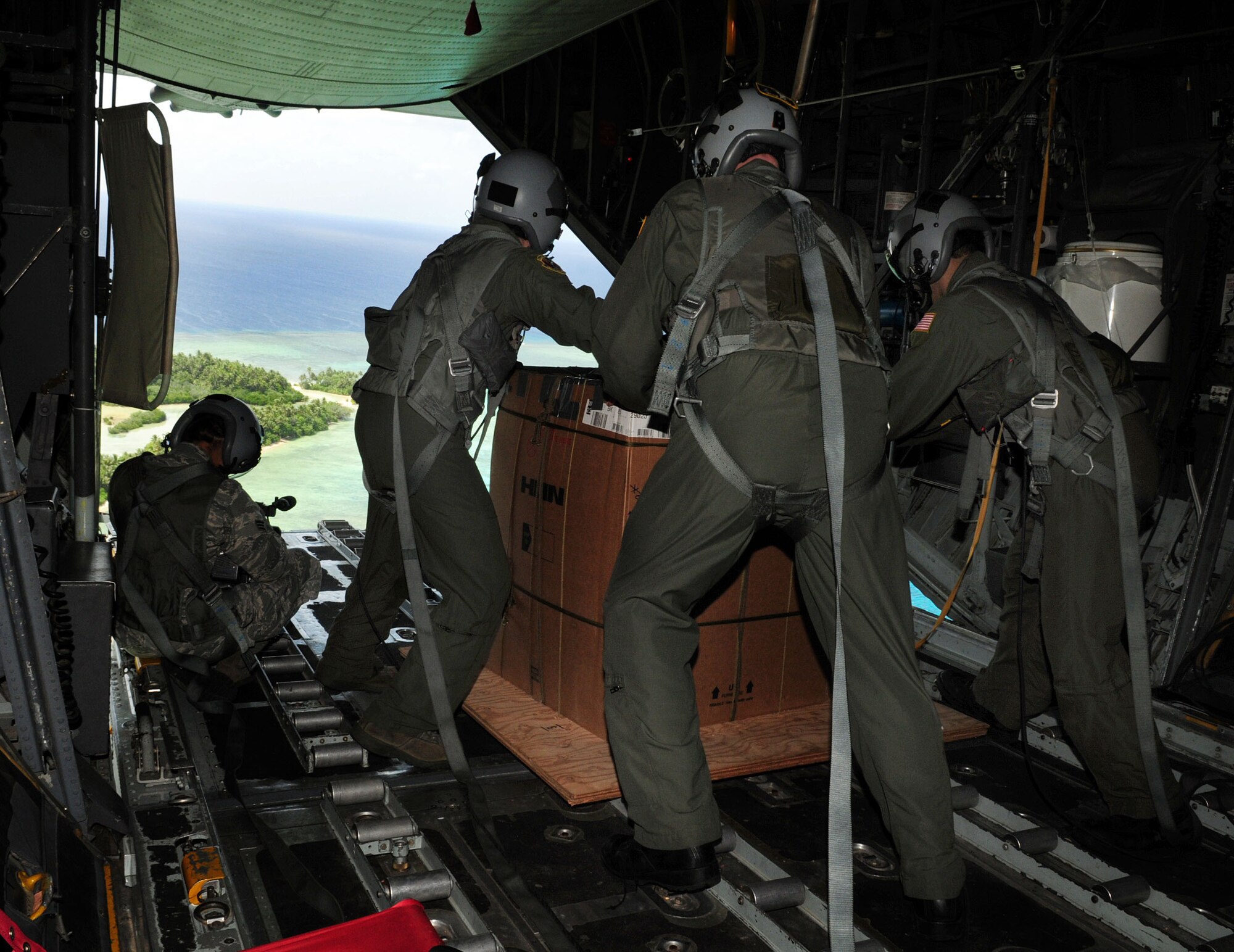 ANDERSEN AIR FORCE BASE, Guam - Airman from the 36th Airlift Squadron, Yokota Air Base, Japan, prepare to drop a package over a remote island near Chuuk Dec. 17. Operation Christmas Drop is a non-profit organization powered by volunteers from Andersen Air Force Base and the local Guam community. Each year, the two join forces to aid over 30,000 islanders in Chuuk, Palau, Yap, Marshall Islands and Commonwealth of the Northern Mariana Islands. (U.S. Air Force photo by Airman 1st Class Courtney Witt)  