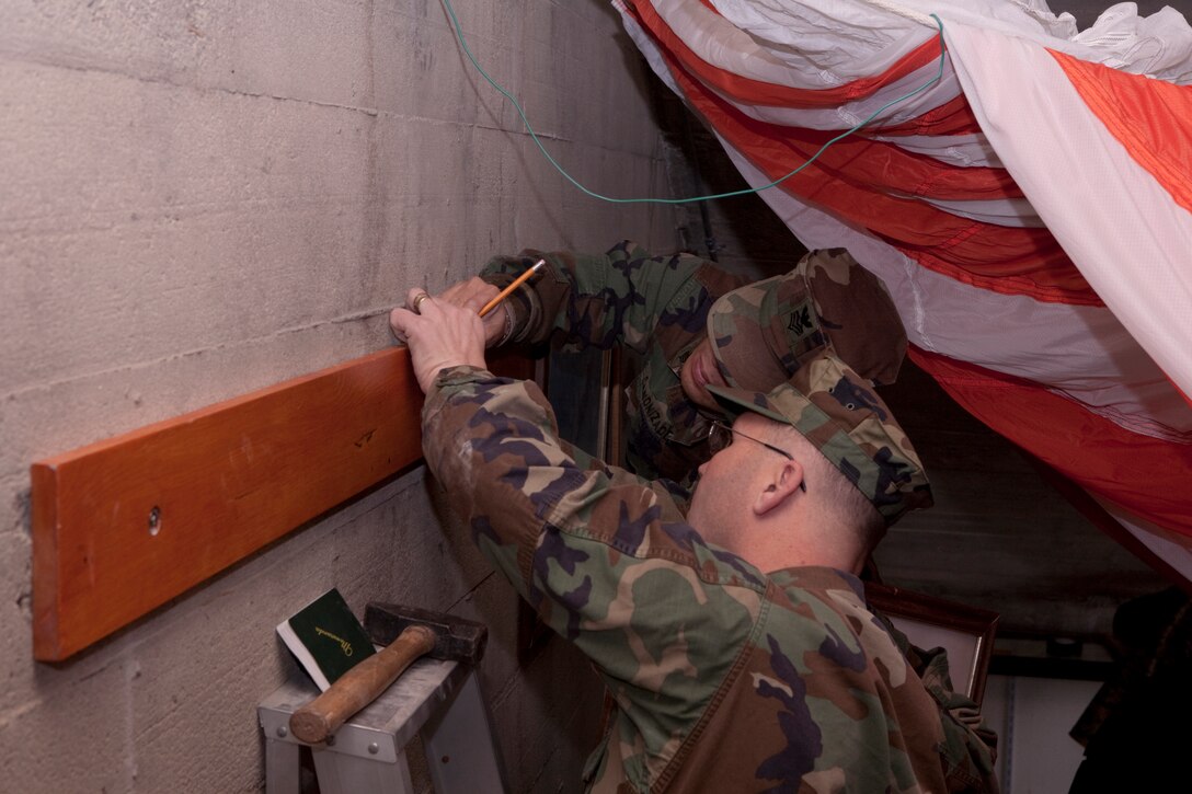 Petty Officer's First Class Bobby Wilson and Cesar Canonizado take measurements in preparation for hanging a picture during a Zero Hangar cleanup and beautification event here Dec. 17. Wilson and Canonizado were just a couple of members of the First Class Petty Officer's Association who gave their time to tidy up the Zero Hangar.