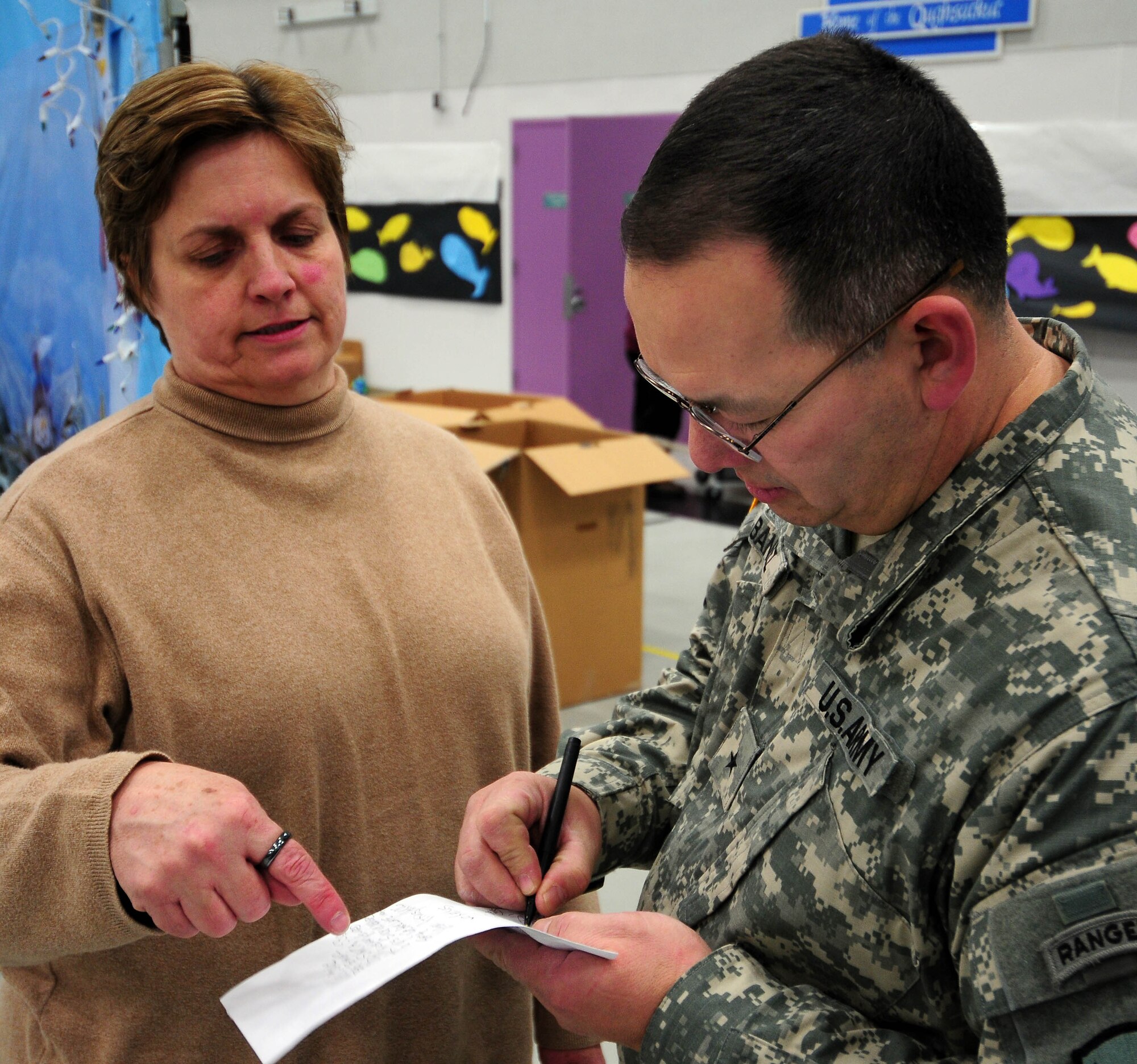 Brig. Gen. Randy Banez (right), assistant adjutant general for the Alaska Army National Guard, prepares short remarks for schoolchildren at Gambell Public School with help from Jan Meyers, the Alaska National Guard's state family programs director. The Alaska Air and Army National Guard were in Gambell, on remote St. Lawrence Island in the Bering Sea, with a group of civilian volunteers on Dec. 16, 2009 as part of Operation Santa Claus. Now in its 53rd year, Operation Santa Claus is a program of the Alaska National Guard to bring toys, food, supplies and Christmas cheer to isolated villages around the state. Alaska Air National Guard photo by 1st. Lt. John Callahan.