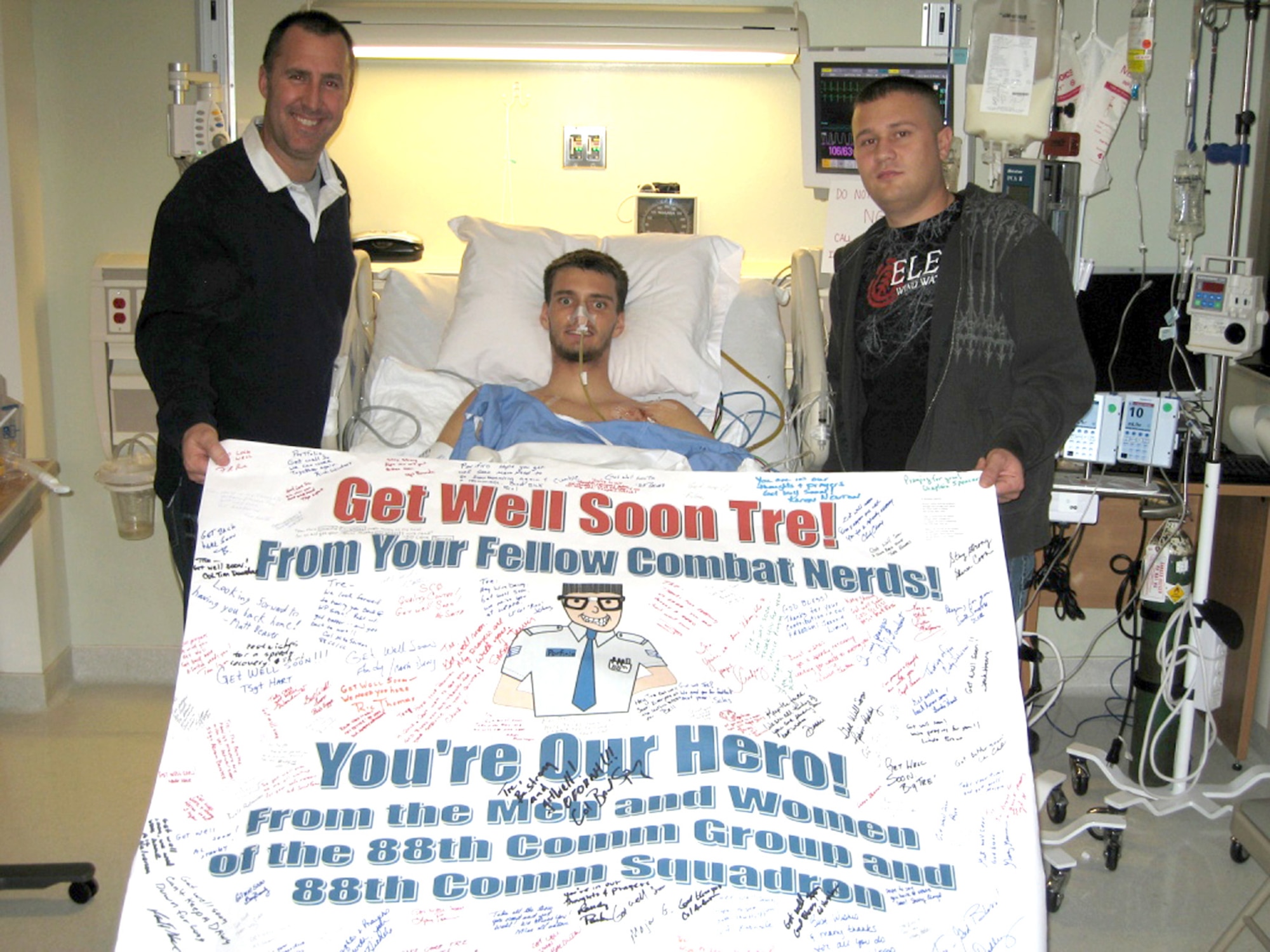 Senior Airman Tre Porfirio poses with Lt. Col. Rick Johns and Senior Airman Scott Cross in his recovery room at Walter Reed Army Medical Center, Md., after receiving 11 surgeries to reconstruct his abdomen. While serving with an Army unit in Afghanistan, Airman Porfirio was shot three times in the back by an insurgent Nov. 21. Airmen Porfirio and Cross are assigned to the 88th Communications Squadron at Wright-Patterson Air Force Base, Ohio. Colonel Johns is the 88th CS commander. 