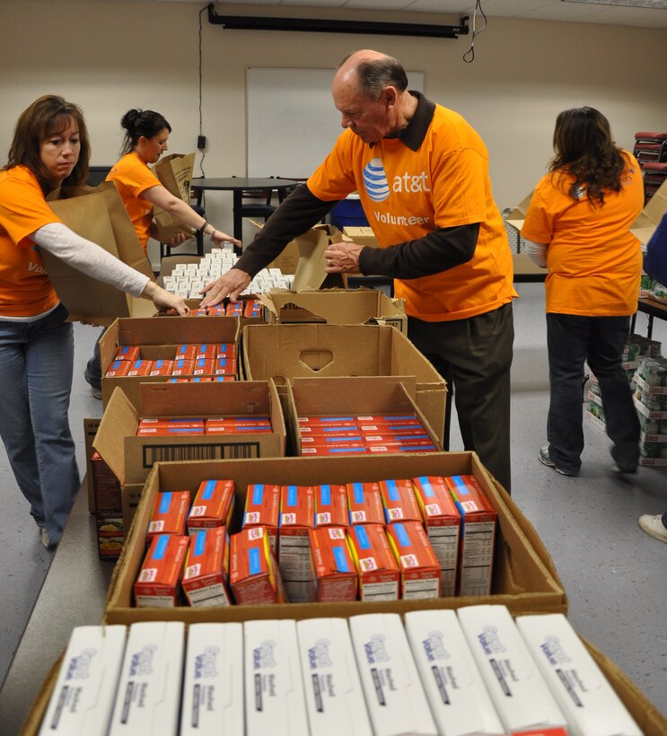 Volunteers from the AT&T Telephone Pioneers of America help fill Christmas bags with dinner items to help Airmen in need at the Airman and Family Readiness Center Dec. 18. The TPA is a non-profit organization that assists all types of people in need, from elementary schools to the elderly. The proceeds are from the annual Motorcycle Ride for the Troops. (U.S. Air Force Photo/Airman 1st Class Adawn Kelsey)