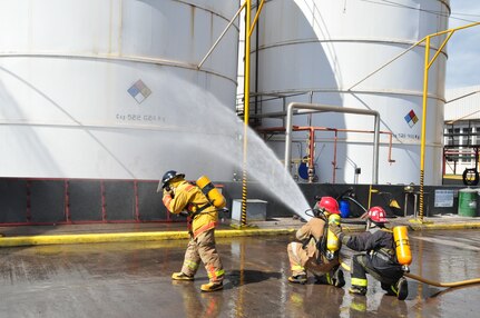 Firefighters from Comayagua, Honduras, spray water on a large storage tank during an industrial fire exercise between U.S. and Honduran firefighters designed to increase their capabilities in working together. (U.S. Air Force photo/Tech. Sgt. Mike Hammond)