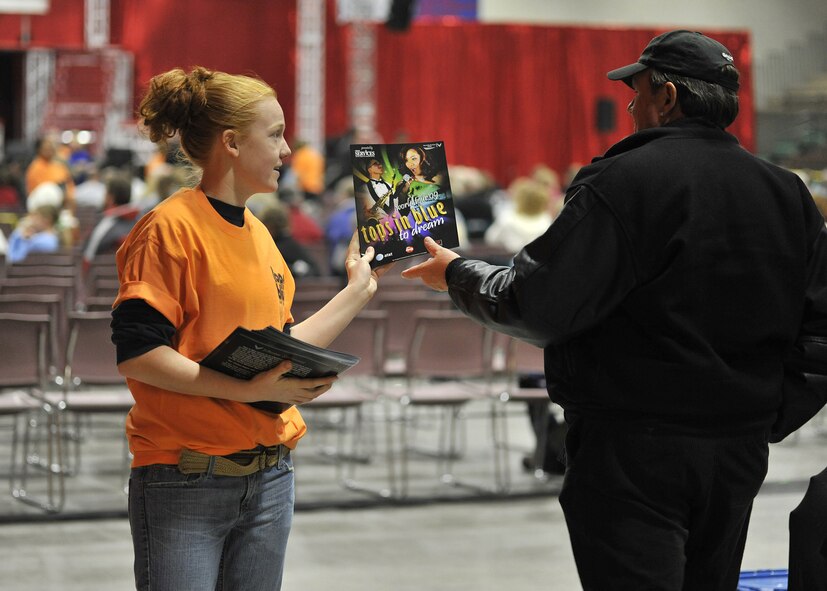 Senior Airman Sahtara Wehe, 16th Munitions Squadron, hands out programs for the Tops In Blue performance Dec. 10 at the Four Seasons Arena in Great Falls, Mont. (U.S. Air Force photo/John Turner)