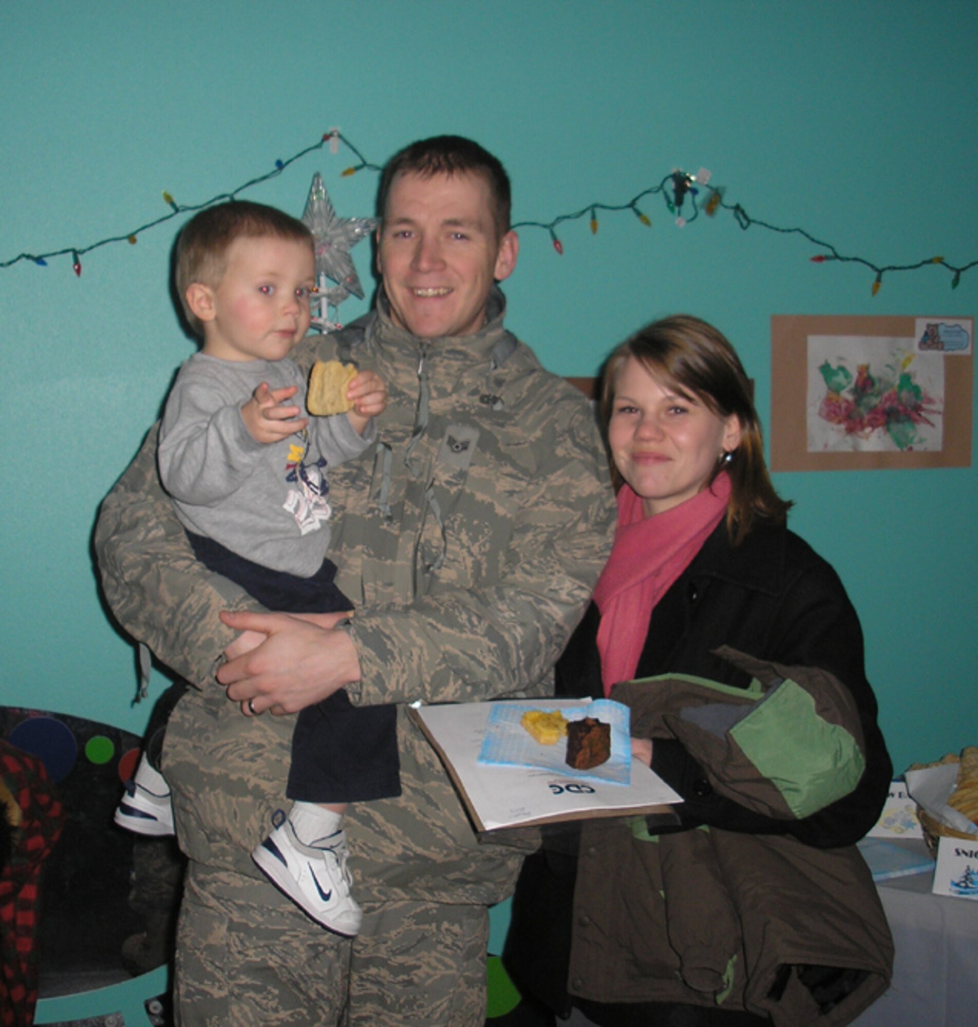 Senior Airman Clint Johnson holds his son Hayde. He and his wife, Laurie, attended the Christmas tea party Dec. 11 and enjoyed cookies and hot chocolate with their son and the otehr children. (Courtesy photo)