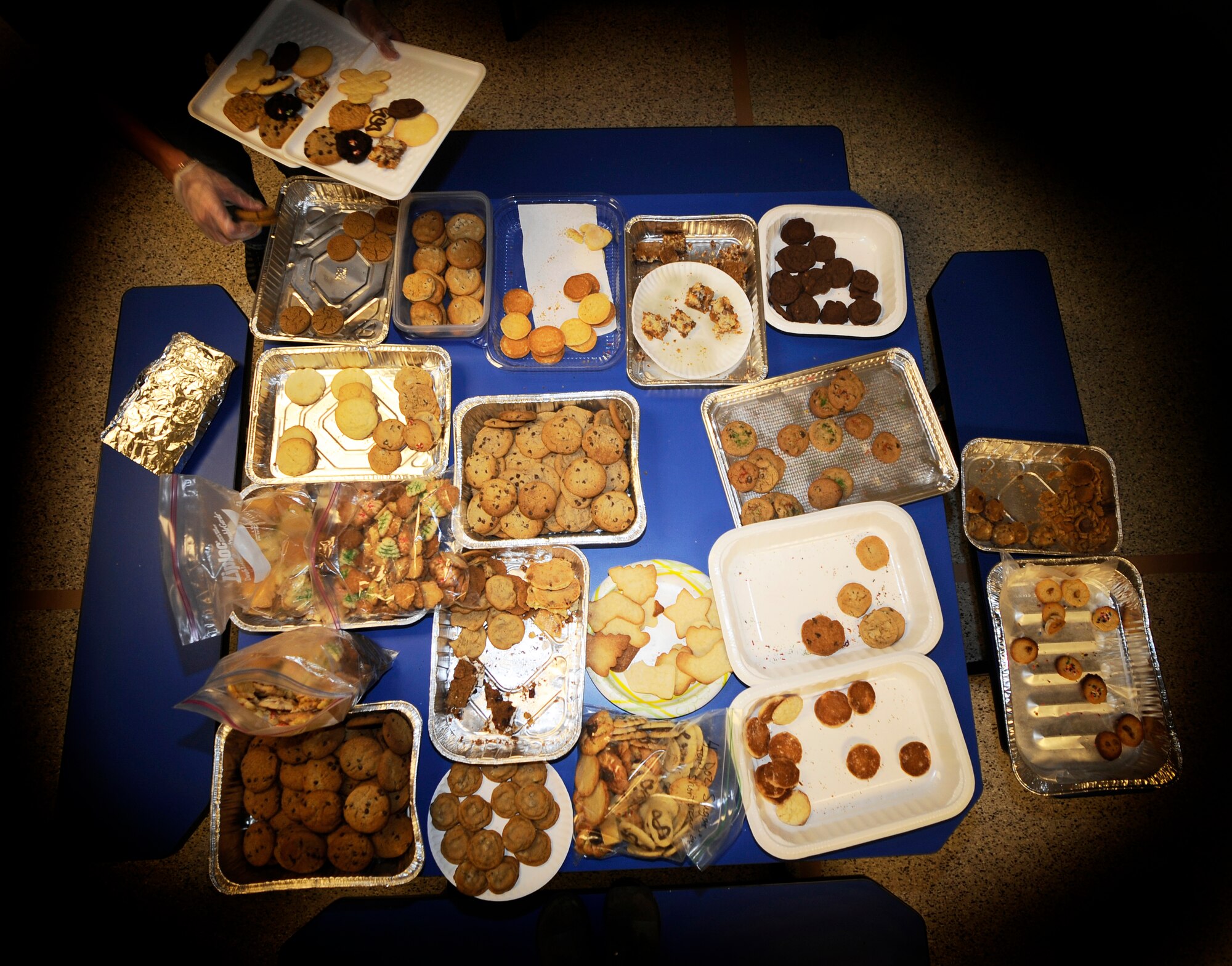 HOLLOMAN AIR FORCE BASE, N.M. -- Jaime Sherwood, wife of Ryan Sherwood, 6th Reconnaissance Squadron, picks a dozen cookies from each table during the Holloman Officers' Spouses Club cookie drive held at the base commissary here, Dec. 14. Volunteers throughout the base and Alamogordo baked cookies to show their appreciation for the Airmen. The commissary opened their doors on Monday to support the cookie drive. (U.S. Air Force photo illustration by Airman 1st Class Veronica Stamps)	
