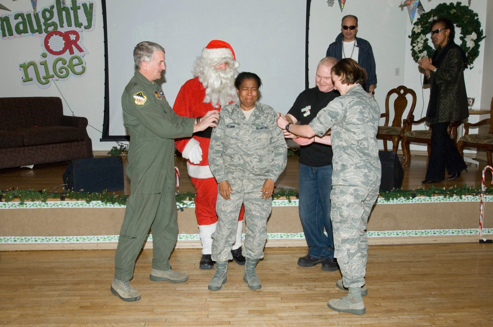 Maj. Gen. David Eichhorn (left), Air Force Flight Test Center commander, and Col. Jerry Gandy, 95th Air Base Wing commander and Capt. Erin Sturgell, 95th Medical Operations Squadron Physical Therapy Flight commander, tack on a new stripe for Master Sgt. Tonya Freeman, 95th Medical Operations Squadron Physical Therapy Flight noncommissioned officer in charge, during the 95th ABW Naughty or Nice Holiday Party Dec. 16, as Santa Claus, Col. Joe Torres, 95th ABW vice commander and Col. Janet Taylor, 95th Medical Group commander, look on. Sergeant Freeman was promoted to the rank of master sergeant through the Stripes to Exceptional Performers program, or STEP. (Air Force photo/Edward Cannon)