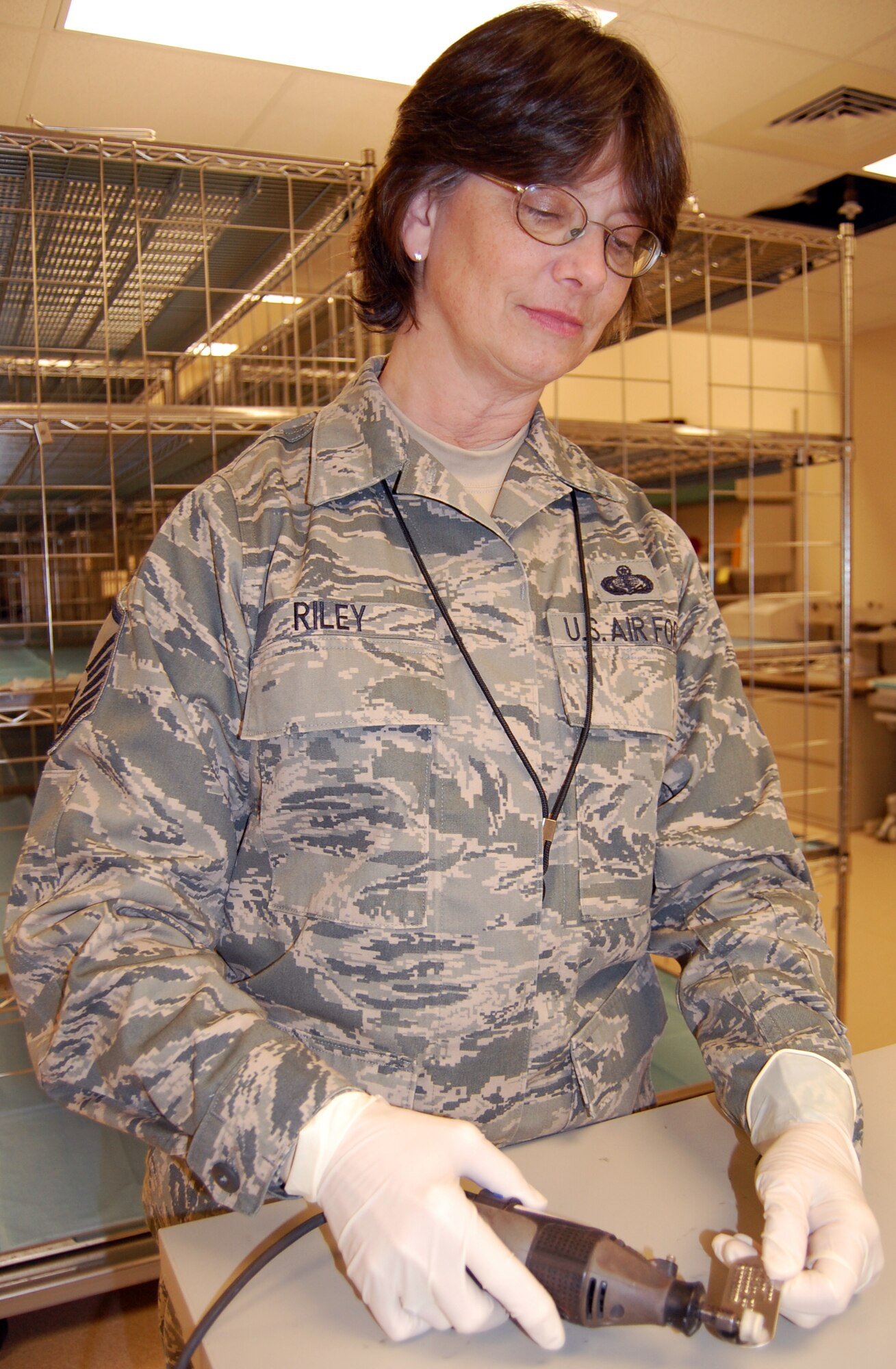 Master Sgt. Judy Riley uses a rotary tool to polish a fallen service member's dog tag so it can be returned to the family.  Sergeant Riley is deployed from the 940th Wing Services Squadron, Beale Air Force Base, Calif., to the Air Force Mortuary Affairs Operations Center, Dover Air Force Base, Del.  (U.S. Air Force photo/Ed Drohan)