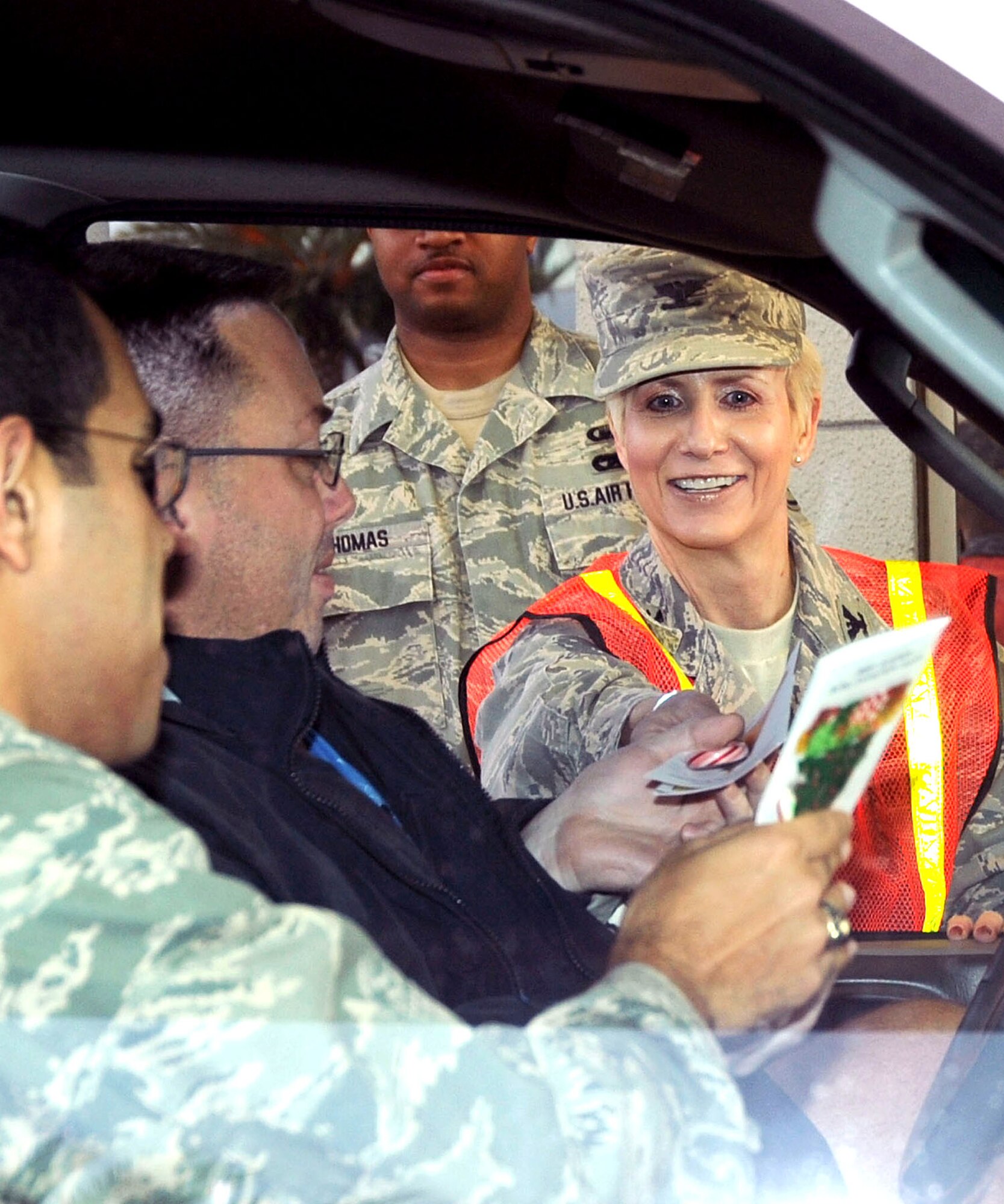 Motorists get a pleasant surprise from Col. Anita Latin (right), 61st Air Base Wing commander, as they drove into work early morning, Dec. 17.  Colonel Latin greeted everyone at the front gate with a smile, a candy cane and copy of the Los Angeles Air Force Base Holiday Bulletin. (Photo by Lou Hernandez)
