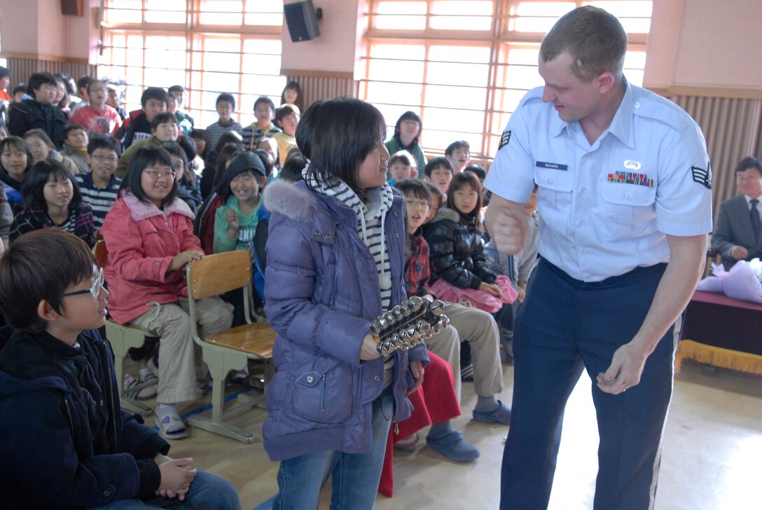 Senior Airman Brandon Richard, member of the Alaska Brass Band from Elmendorf Air Force Base, Alaska, helps a student from Jangdang Elementary School play a percussion instrument Dec. 16. The Alaska Brass visited Osan Air Base and its surrounding areas Dec. 14-19. (U.S. Air Force photo by Staff Sgt. Terri Barriere)