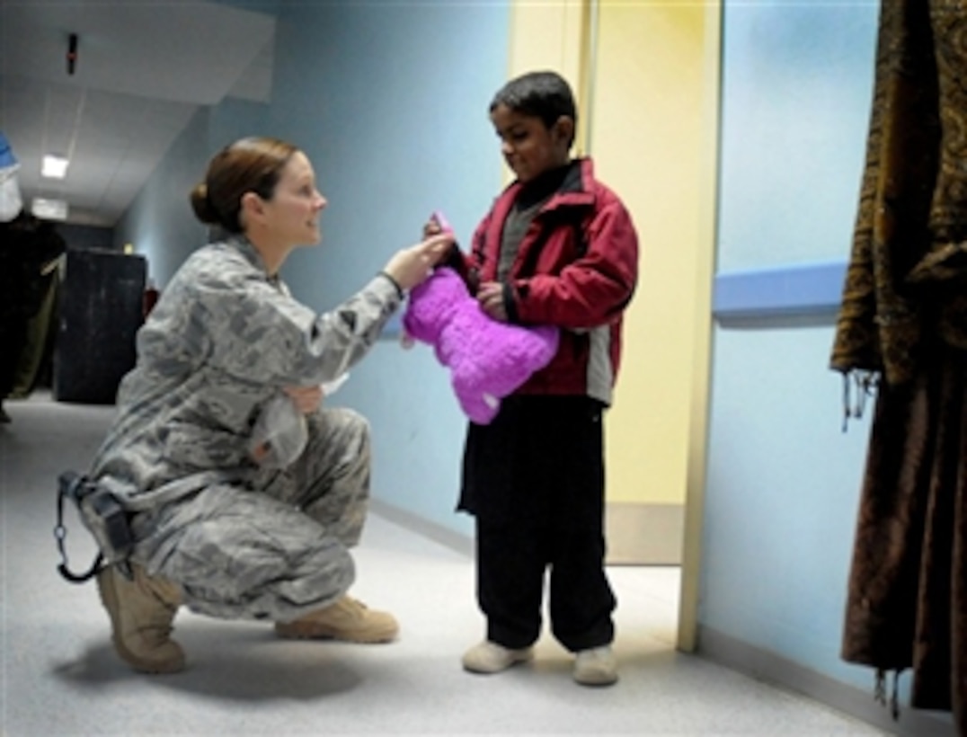 U.S. Air Force Capt. Tess Marcial, a logistics and patient administrator deployed from the 10th Medical Group, U.S. Air Force Academy, hands a toy animal and candies to an Afghan child in Paktya province, Afghanistan, on Dec. 14, 2009.  The child was visiting the 203rd Corps Paktya Regional Military Hospital as a patient at the Women's and Children's Clinic.  