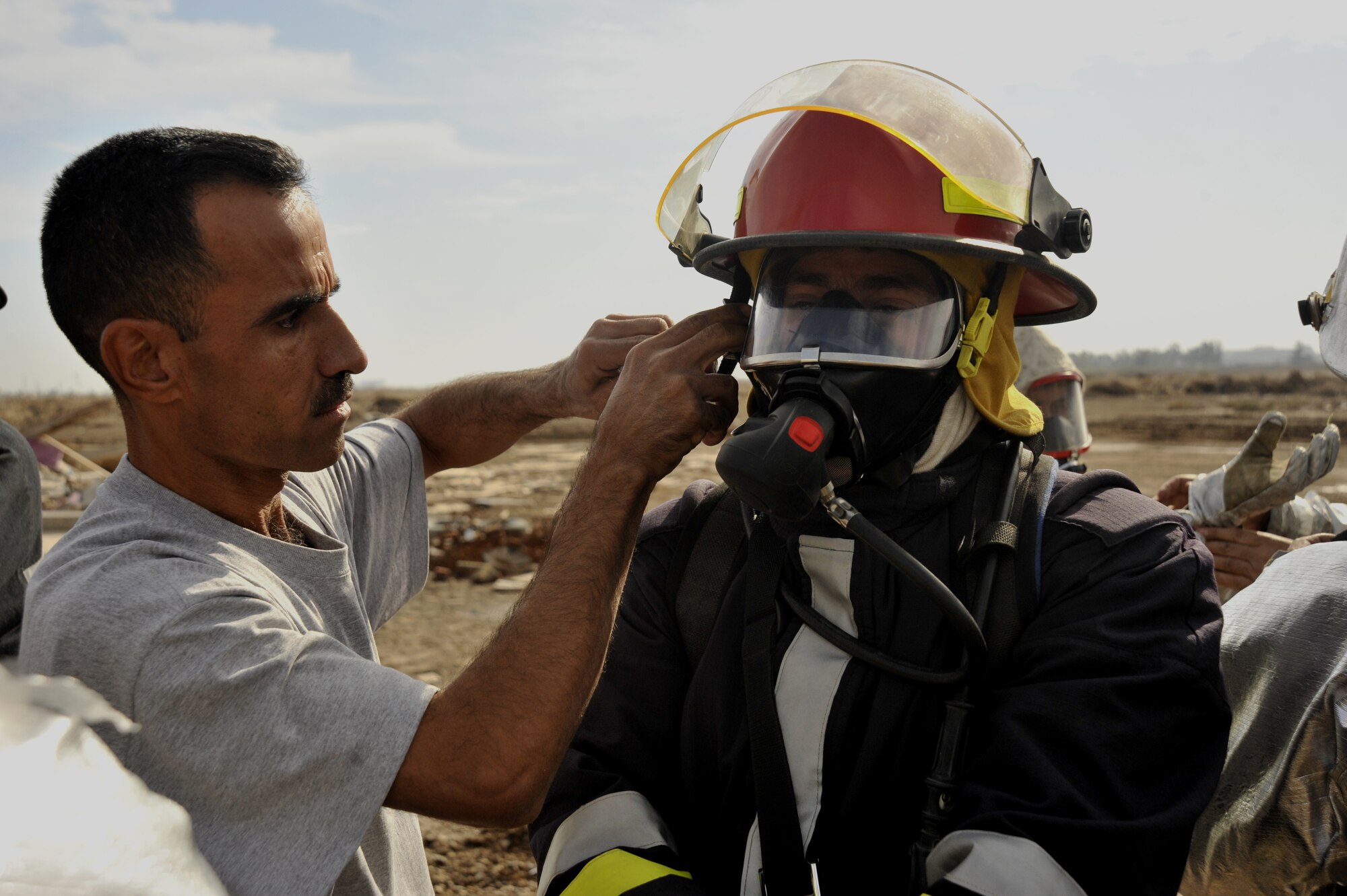 Iraqi fire fighters help each other put on gear before they conduct a live training exercise north of Sather's flightline Dec. 16,2009. The Iraqi firefighters gave a live demonstration with the help of Air Force Fire fighters to Major Gen. James Hunt, deputy commander of Multi-National Corps- Iraq. (U.S. Air Force photo/Senior Airman Eric Summers Jr./ released)