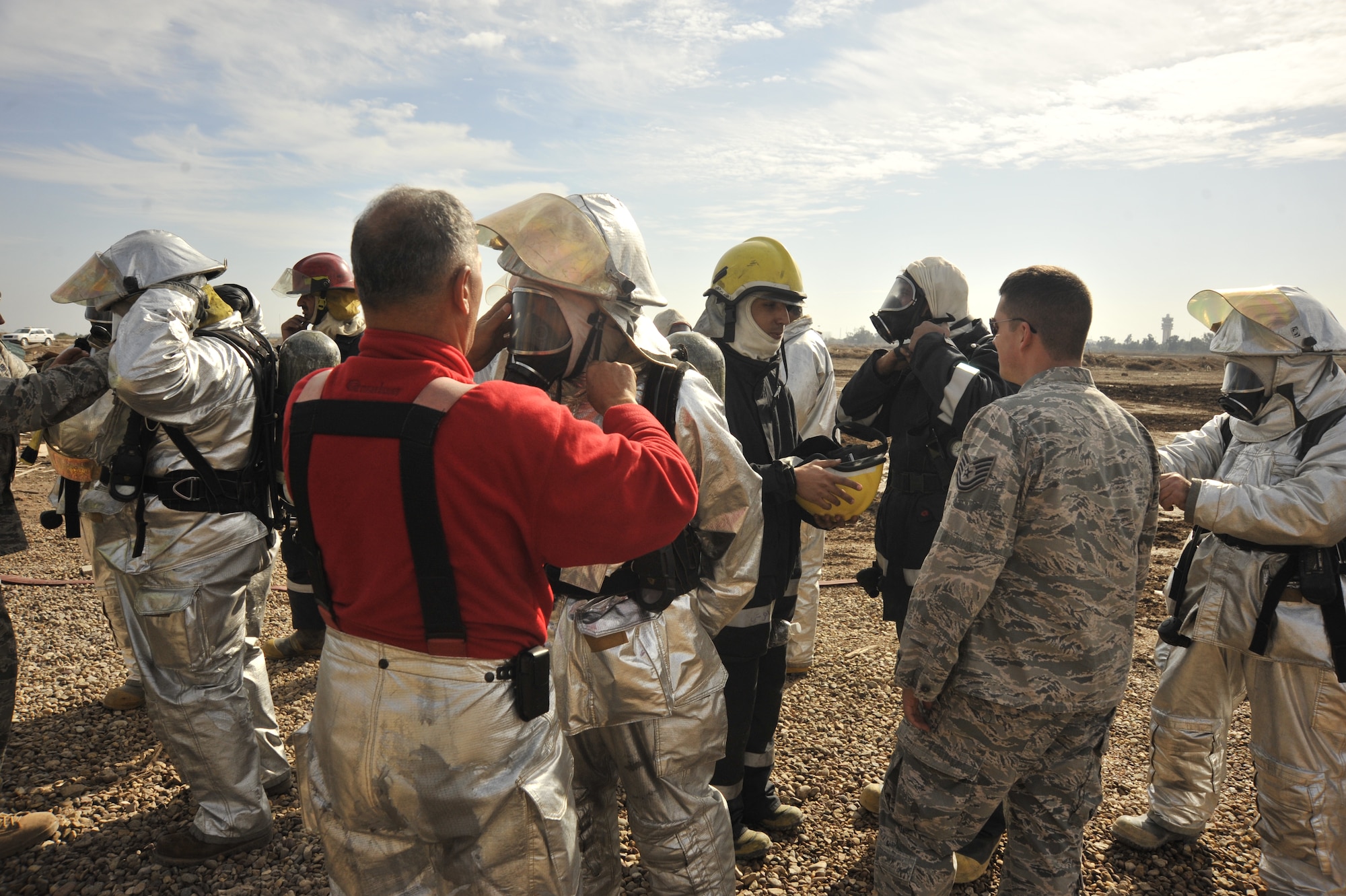 The Iraqi fire chief helps one of the Iraqi fireman put on protective gear before they conduct a live training exercise north of Sather's flightline Dec. 16, 2009. The Iraqi fire fighters gave a live demonstration with the help of Air Force fire fighters to Major Gen. James Hunt, deputy commander of Multi-National Corps- Iraq. (U.S. Air Force photo/Senior Airman Eric Summers Jr./ released)