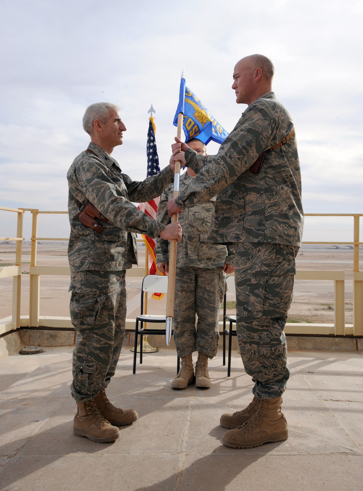 AL ASAD AIR BASE, Iraq -- Air Force Col. David Lujan (left), 332nd Expeditionary Operations Group Commander, hands the guidon to Lt. Col. Barry Dickey, incoming commander for the 532nd Expeditionary Operations Support Squadron during the assumption of command ceremony Dec. 15, 2009. The airfield was previously operated by the U.S. Marine Corps, but due to the drawdown, the Air Force has taken over these responsibilities. (U.S. Air Force photo/Master Sgt. Trish Bunting)