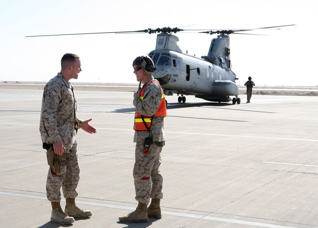 Second Lt. Amaury Gallais, officer-in-charge of the Arrival and Departure Airfield Control Group here, speaks with  one of his Marines on the flight line during a routine operation Dec. 19, 2009.  Gallais, 29, was a lance corporal reservist in the infantry before going to OCS and becoming a logistics officer in 2008.