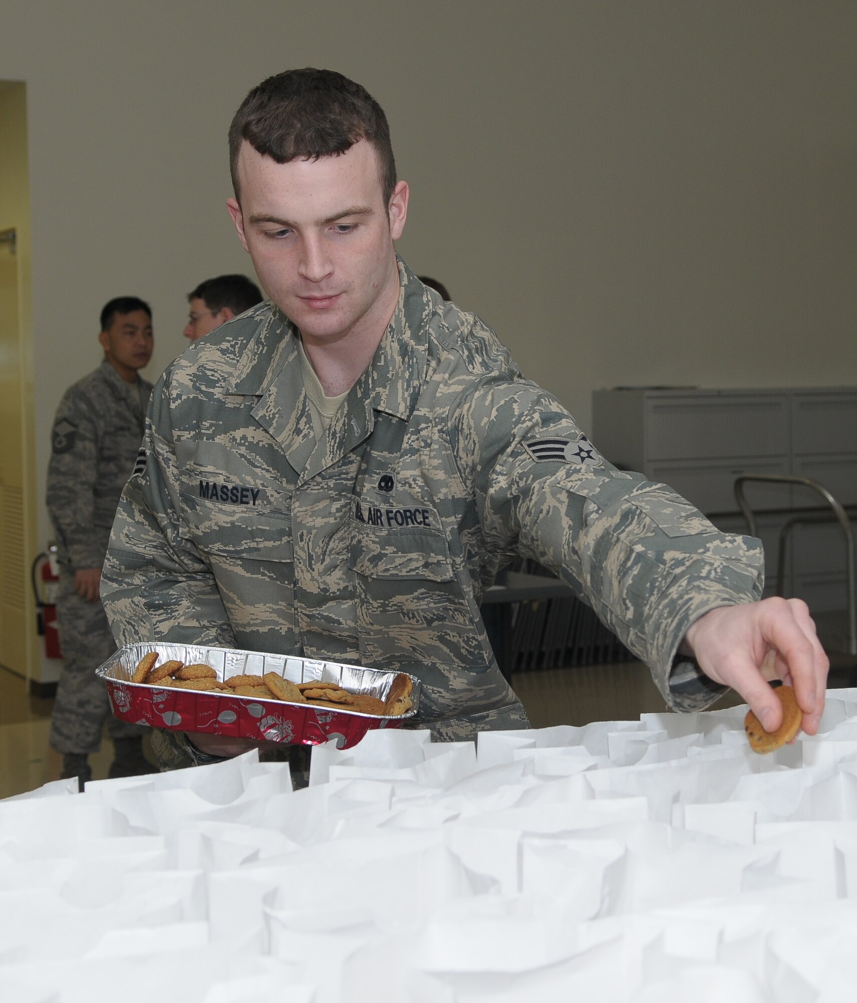 YOKOTA AIR BASE, Japan -- Senior Airman Kenneth Massey, 374th Maintenance Squadron, fills gift bags Dec. 18 during the Cookie Crunch event. More than 3,000 cookies were donated, bagged and distributed to Airmen in the dormitories by the Yokota Enlisted Spouses Club. (U.S. Air Force photo/Airman 1st Class Sean Martin)