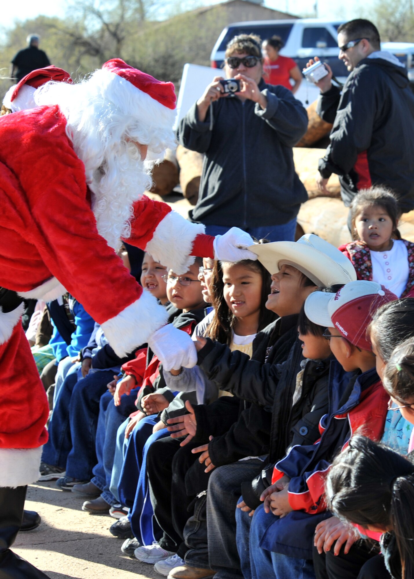 Santa greets students from St. Xavier Mission School Dec. 17. Mr. Claus was at the school to host the Santas in Blue event in which Airmen from across D-M come together to give gifts to children for Christmas. The St. Xavier Mission School has students from kindergarten through eighth grade. (U.S. Air Force Photo/Master Sgt. Heather Cabral)
