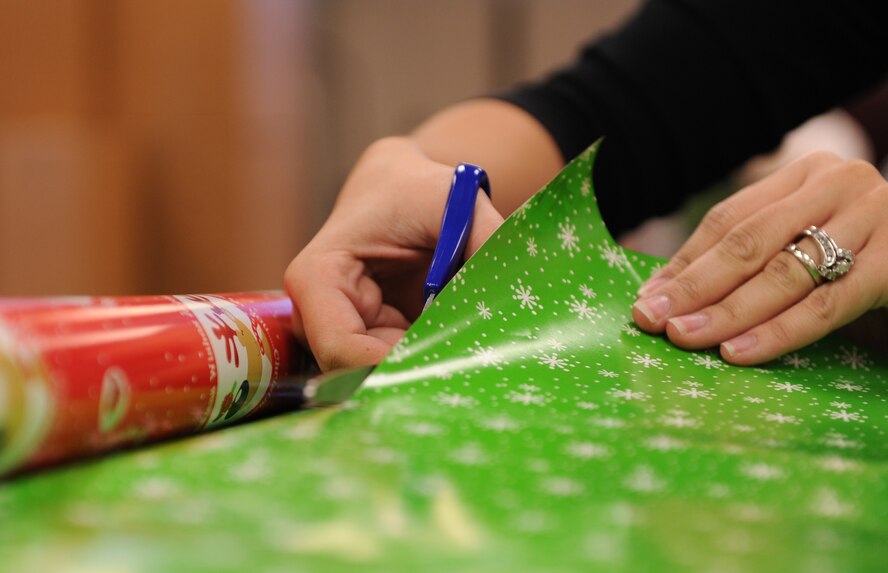 MOODY AIR FORCE BASE, Ga. -- Team Moody members use decorative paper to wrap gifts donated to the Adopt-a-Family program here Dec. 16. The volunteers worked together throughout the day to box and wrap the presents to be sent to families in need this holiday season. (U.S. Air Force photo by Airman 1st Class Benjamin Wiseman)
