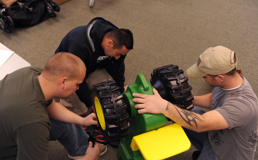 MOODY AIR FORCE BASE, Ga. -- Members of the 23rd Equipment Maintenance Squadron work together to assemble a toy tractor donated to the Adopt-a-Family program here Dec. 16. In the past, Moody donated between $35,000 to $45,000 worth of gifts annually to the Adopt-A-Family program. (U.S. Air Force photo by Airman 1st Class Benjamin Wiseman)