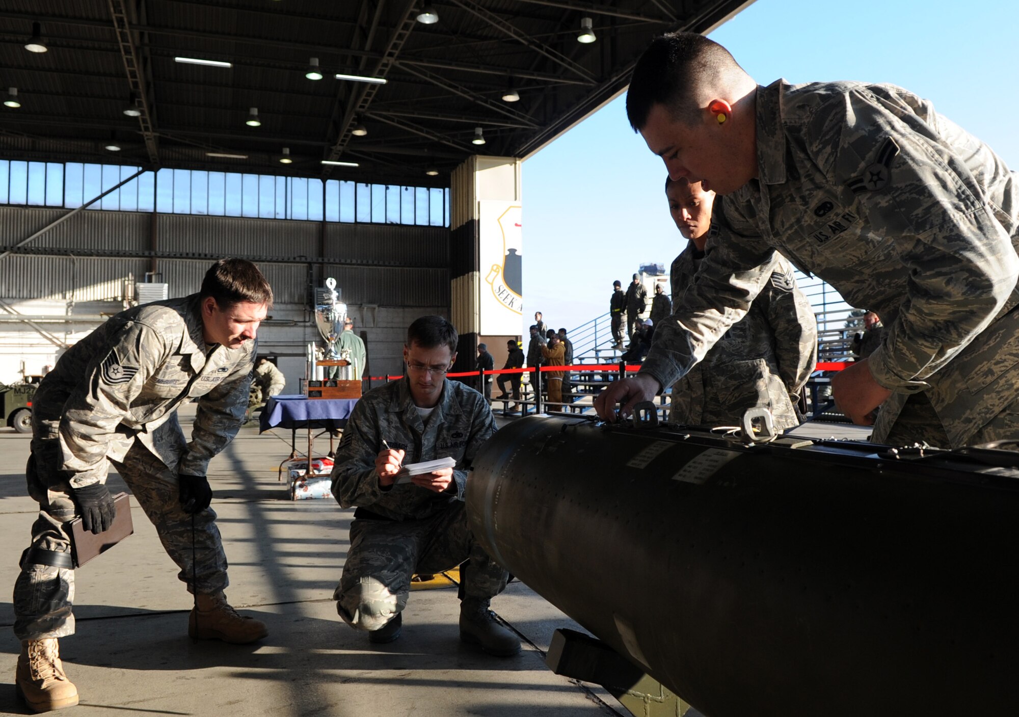 SPANGDAHLEM AIR BASE, Germany – Members from the 22nd Aircraft Maintenance Unit prepare to load a weapon onto an F-16 Fighting Falcon during the fourth quarter Weapons Load Crew Competition Dec. 18. The 22nd and 81st Fighter Squadrons put together three-man teams and competed against each other to load weapons onto an F-16 and an A-10 Thunderbolt II in the fastest time. The 81st FS won the fourth quarter competition. (U.S. Air Force photo/Airman 1st Class Staci Miller)