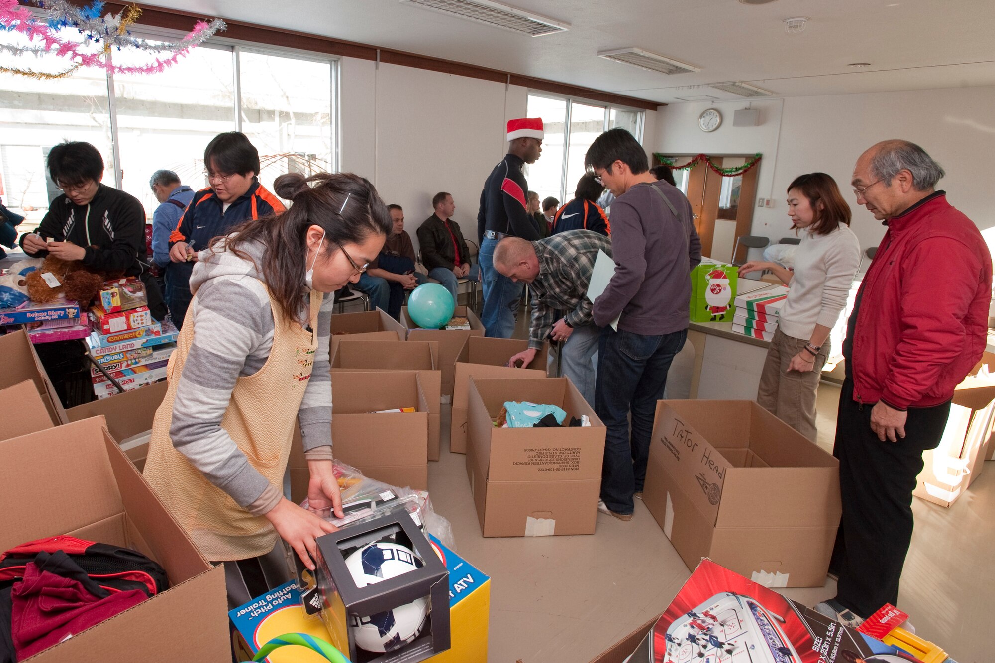 HACHINOHE, Japan -- Members of the Misawa Air Base Chiefs' Group and volunteers from the Koko Gakuen Orphanage open boxes of donated toys Dec. 19. The chiefs' group donated more than 150 toys and arranged a special visit by Santa to distribute gifts to 27 children. (U.S. Air Force photo/Staff Sgt. Samuel Morse)