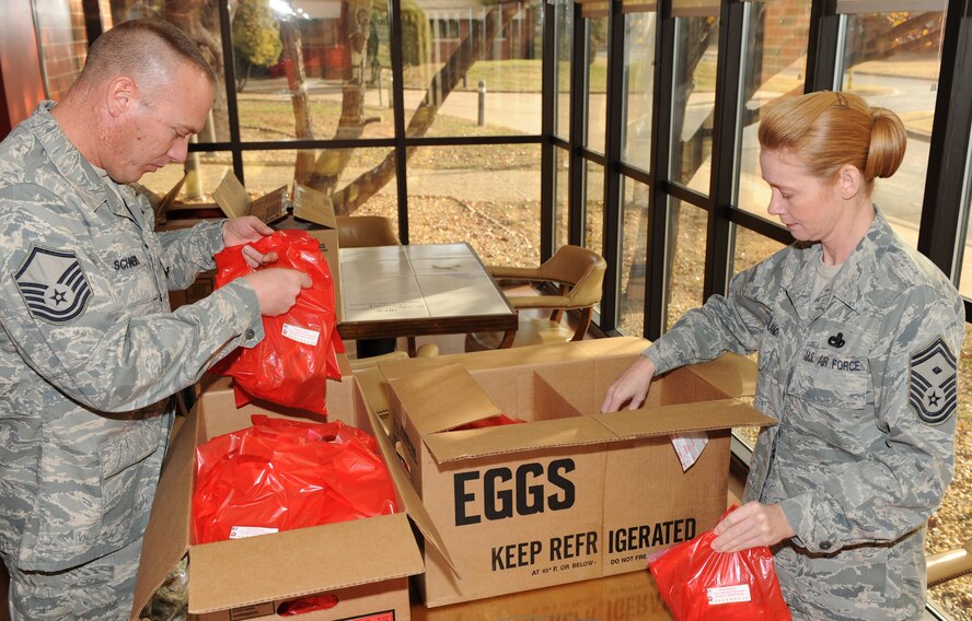 DYESS AIR FORCE BASE, Texas -- Master Sgt. Paul Schneider and First Sgt., Senior Master Sgt. Connie Sutherland, both from the 317th Aircraft Maintenance Squadron, pack donated cookies for the dormitory residents here, Dec. 21.  Every year the First Sgts. collect home made cookies from base members to hand out to the dorm residents during the holiday season.  (U.S. Air Force photo/ Staff Sgt. Tanya Bowen)