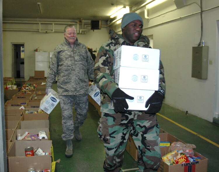 TACOMA, Wash.- Master Sgt. Steven Thomas, right, superintendant of the 446th Mission Support Group Airman and Family Readiness Center, McChord Air Force Base, Wash. and 446th MSS Airman and Family Readiness technician, Tech. Sgt. Rick Martini, carry cases of milk to load on to a truck this morning. The milk, along with bags of potatoes, ham, and non-perishable goods were collected by Central Pierce County Fire and Rescue here and given to the Airman and Family Readiness Center to distribute to Reserve families in need today. For about the last five years, the Airman and Family Readiness Center and CPFR have worked together to help needy families. More than 30 boxes were given to families. (U.S. Air Force photo/Master Sgt. Jake Chappelle)