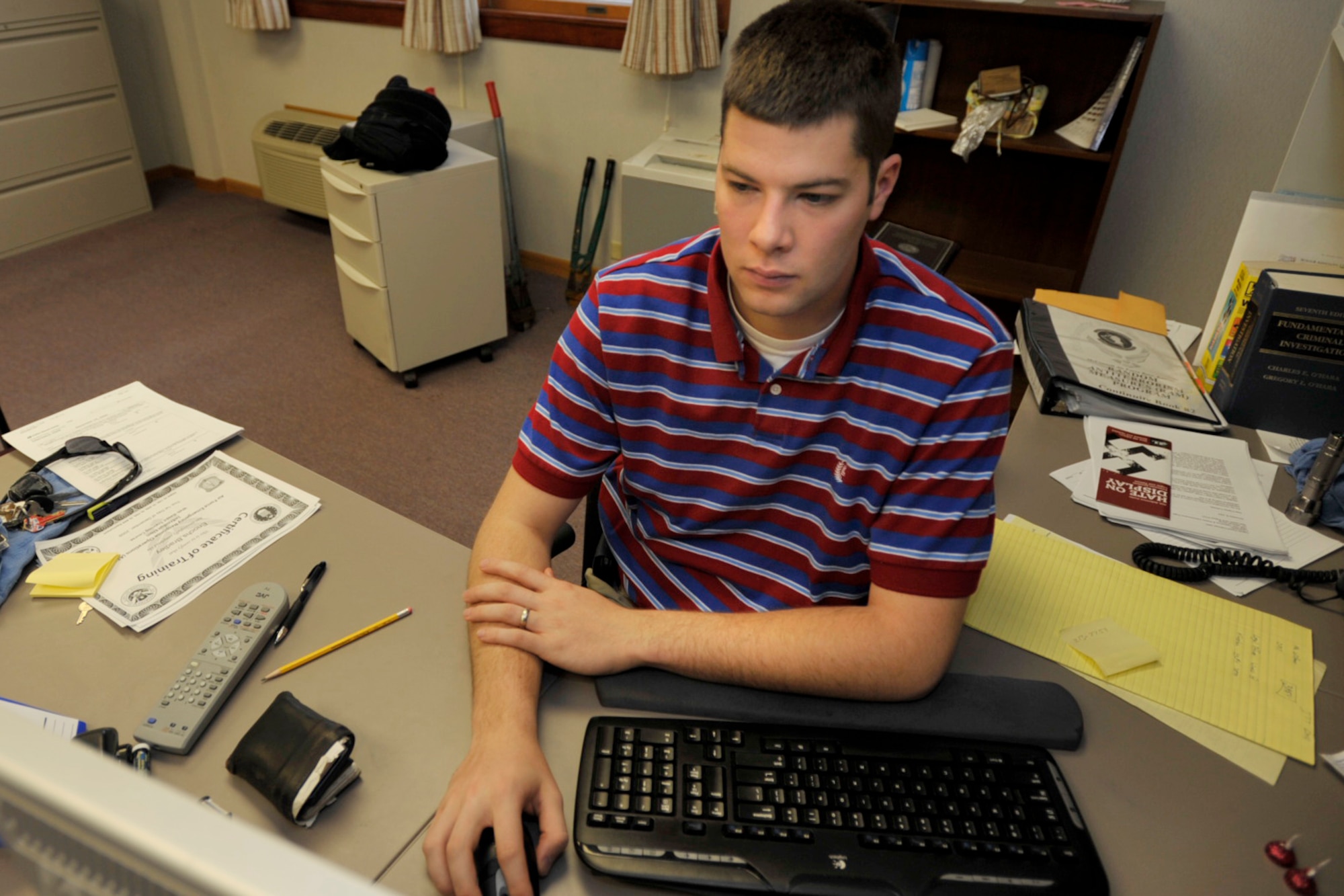 Investigator Brad Enochs works in his office at McConnell Air Force Base, Kan. A Reserve senior airman assigned to the 931st Air Refueling Group's security forces team, Airman Enochs has been working full-time at the base filling in for deployed active-duty security forces Airmen. (U.S. Air Force photo/Master Sgt. Jason Schaap)