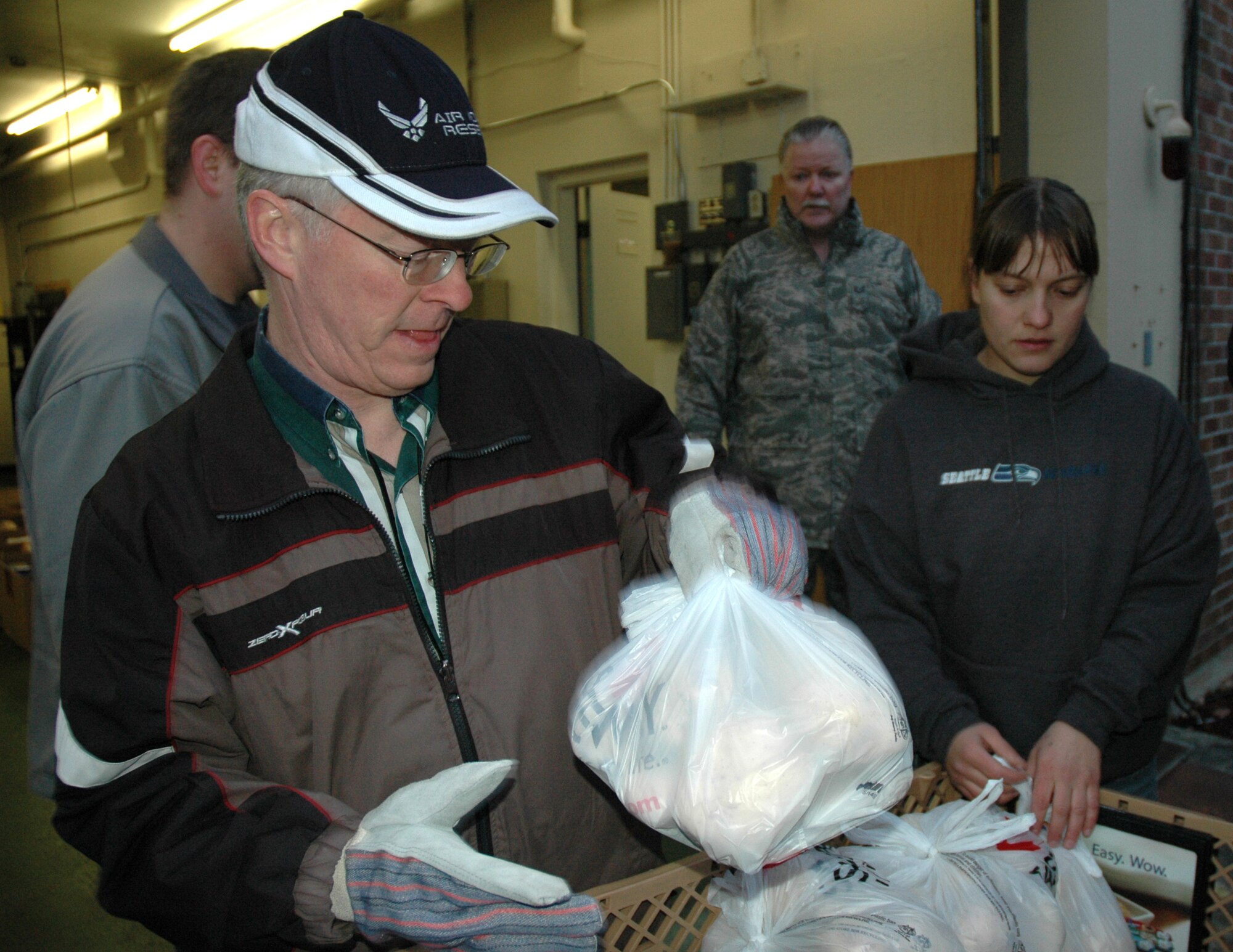 TACOMA, Wash.- 446th Mission Support Squadron Airman and Family Readiness Center, McChord Air Force Base, Wash. director, Carl Supplee, left, helps load bags of potatoes along with, Tech. Sgt. Rick Martini, center, 446th MSS Airman and Family Readiness assistant, and Tami Klube, a firefighter with Central Pierce County Fire and Rescue here on to a truck. The potatoes, along with, milk, ham, and boxes of non-perishable goods were collected by CPFR and given to the Airman and Family Readiness Center to be distributed to needy Reserve families at McChord AFB. The Airman and Family Readiness Center has been working with CPFR for about the last five years to help give families in need some extra food for the holidays. (U.S. Air Force photo/Master Sgt. Jake Chappelle)