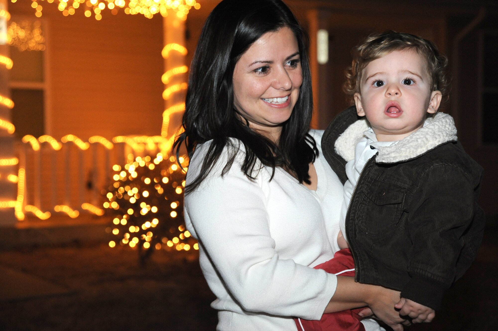 Team McConnell family members, Vivianne King and son Jaden, 11 months, step outside of their home in Southwind base housing to hear McConnell carolers sing holiday songs, Dec. 20, 2009, at  McConnell Air Force Base, Kan. Carolers visited more than 130 homes in base housing.  (U.S. Air Force photo by Tech. Sgt. Chyrece Campbell)