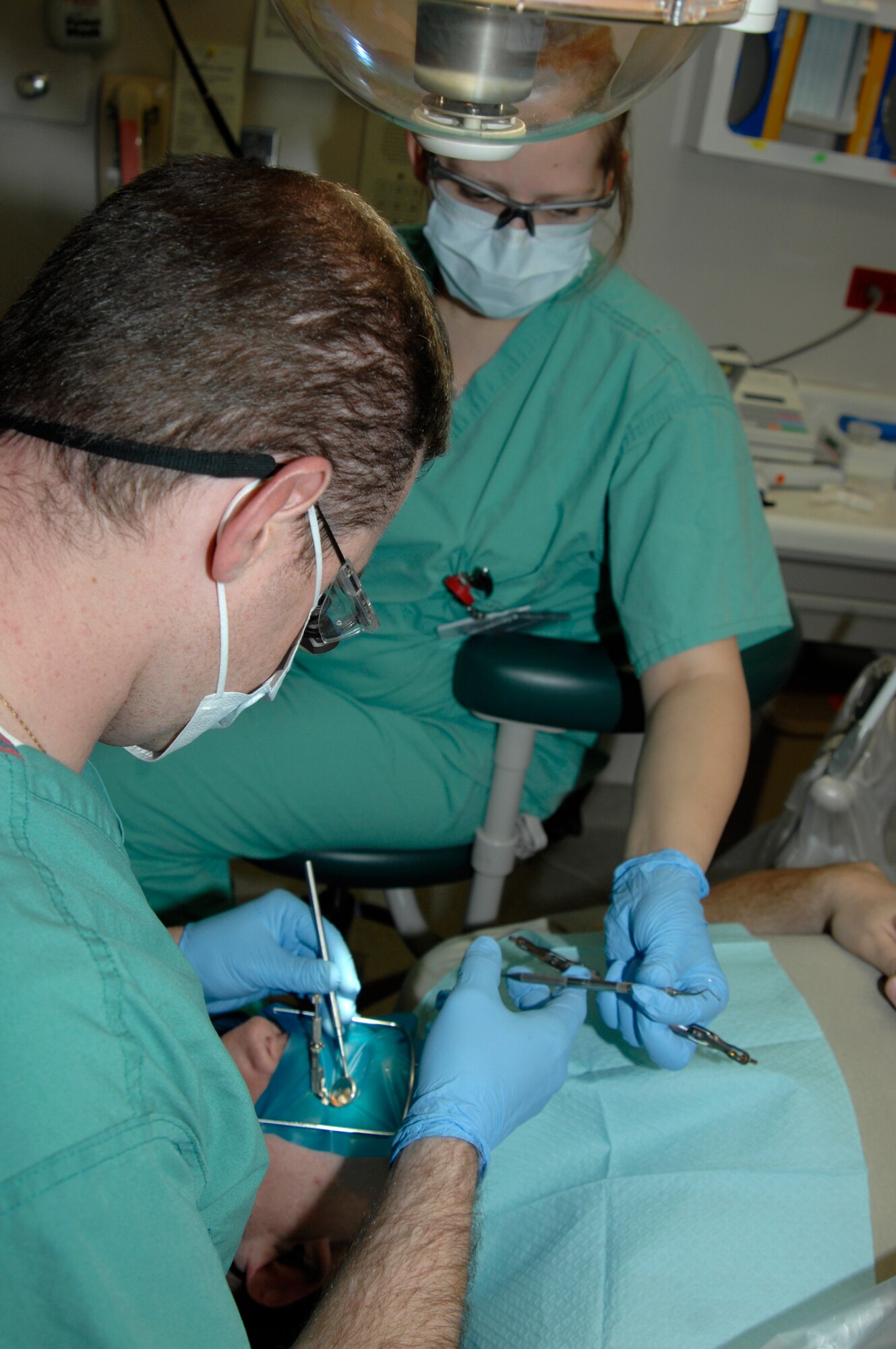 Capt. Todd Schultz, a 22nd Aero-Medical Dental Squadron dentist, fills a cavity on a patient with the help of Senior Airman Lindsey Bedegi, 931st Aero-Medical Dental Flight, Dec. 14, 2009, at McConnell Air Force Base, Kan. For efficient dental care, Capt. Schultz used a rubber dam, a tool designed to isolate a single tooth to make it easier to work on.  (U.S. Air Force Photo by Airman 1st Class Justin Shelton)