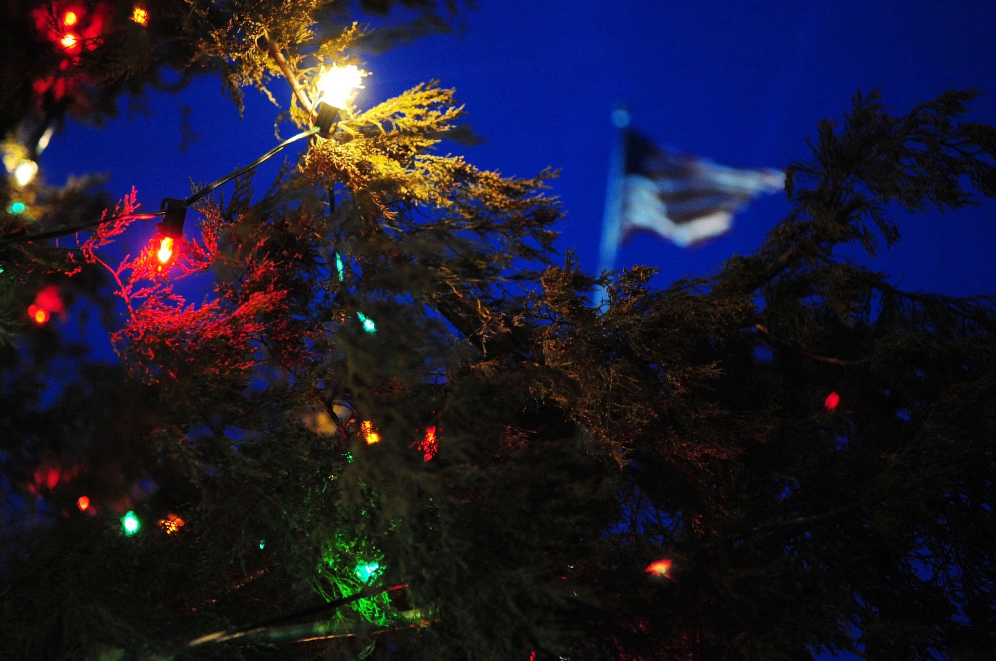 BARKSDALE AIR FORCE BASE, La. -- The American flag can be seen between the lit branches of the base Christmas tree which welcomes Airmen and visitors to the base, their warmth wishing Happy Holidays to all. (U.S. Air Force photo by Senior Airman Joanna M. Kresge)