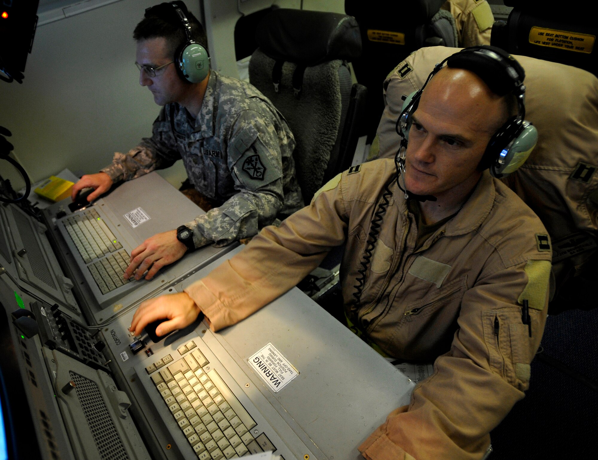 U.S. Air Force Capt. James Bourgeault (right), 7th Expeditionary Air Command and Control Squadron, Joint Surveillance Target Attack Radar System senior director, and U.S. Army Maj. George Whittenburg, deputy mission crew commander, both stationed at Robins Air Force Base, Ga., deployed to Southwest Asia, manage the operations of a JSTARS crew, Dec. 18, 2009.  One way of managing the operation is by collecting data of suspicious moving targets and reporting them to troops on the ground. (U.S. Air Force photo/Staff Sgt. Angelita Lawrence)