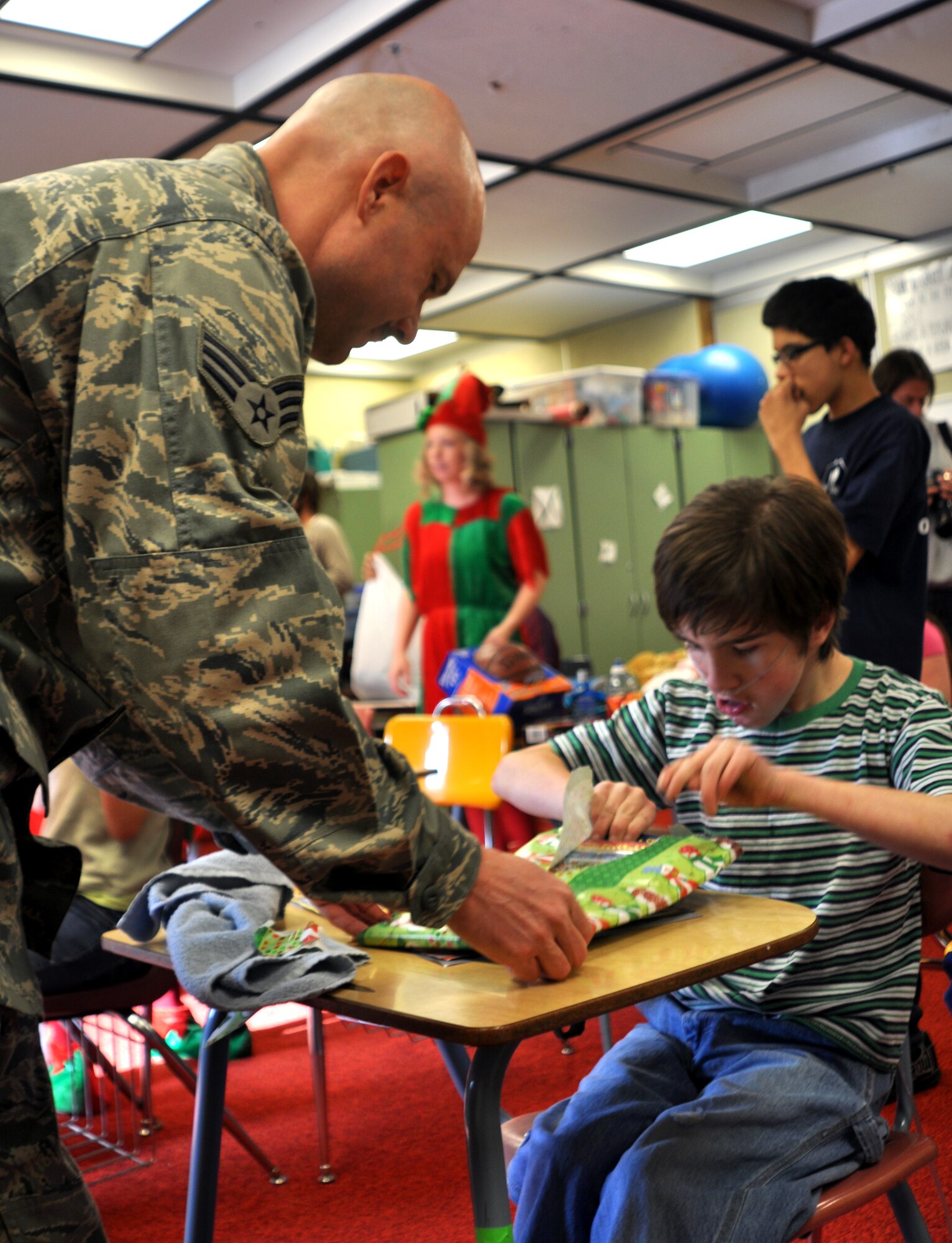 Senior Airman Matthew Brasel, 67th Aerial Port Squadron, lends a hand to Jeremy Dixon, a special needs student at Mound Fort Junior High School in Ogden. The 67th APS has organized the children’s Christmas party each year since 1990, raising money to buy gifts and school supplies for each child. The party includes a surprise visit from Santa. (U.S. Air Force photo/Kari Tilton)