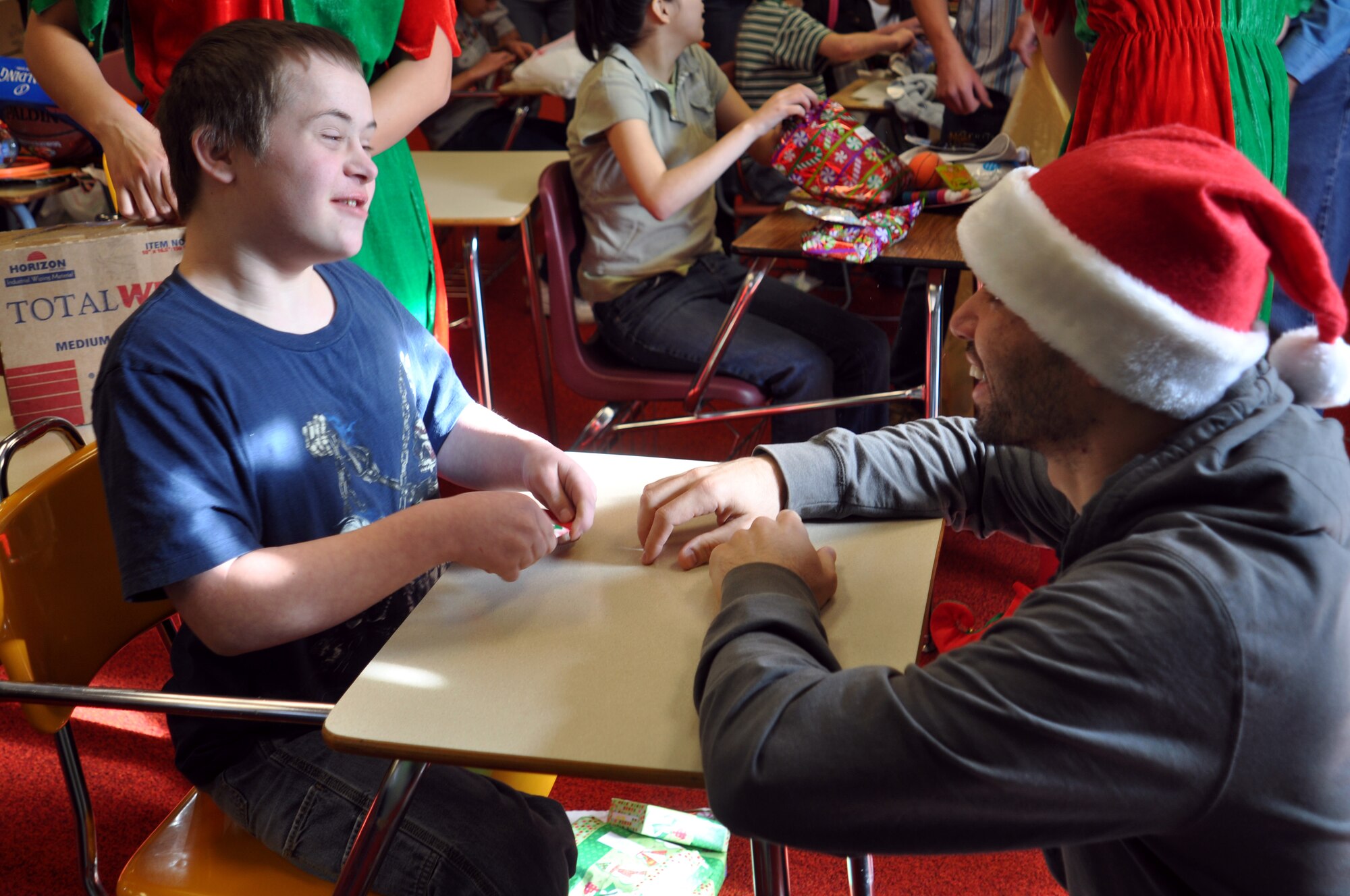 Senior Airman Rahman Badarane, 67th Aerial Port Squadron, chats with Tyler Chapman, a special needs student at Mound Fort Junior High School in Ogden. This was the second year Airman Badarane participated in the children’s annual Christmas party, which the 67th APS has organized each year since 1990. Members of the squadron donate money to buy gifts for each child based on his or her wish-list. The party also features a visit from Santa. (U.S. Air Force photo/Bryan Magaña)