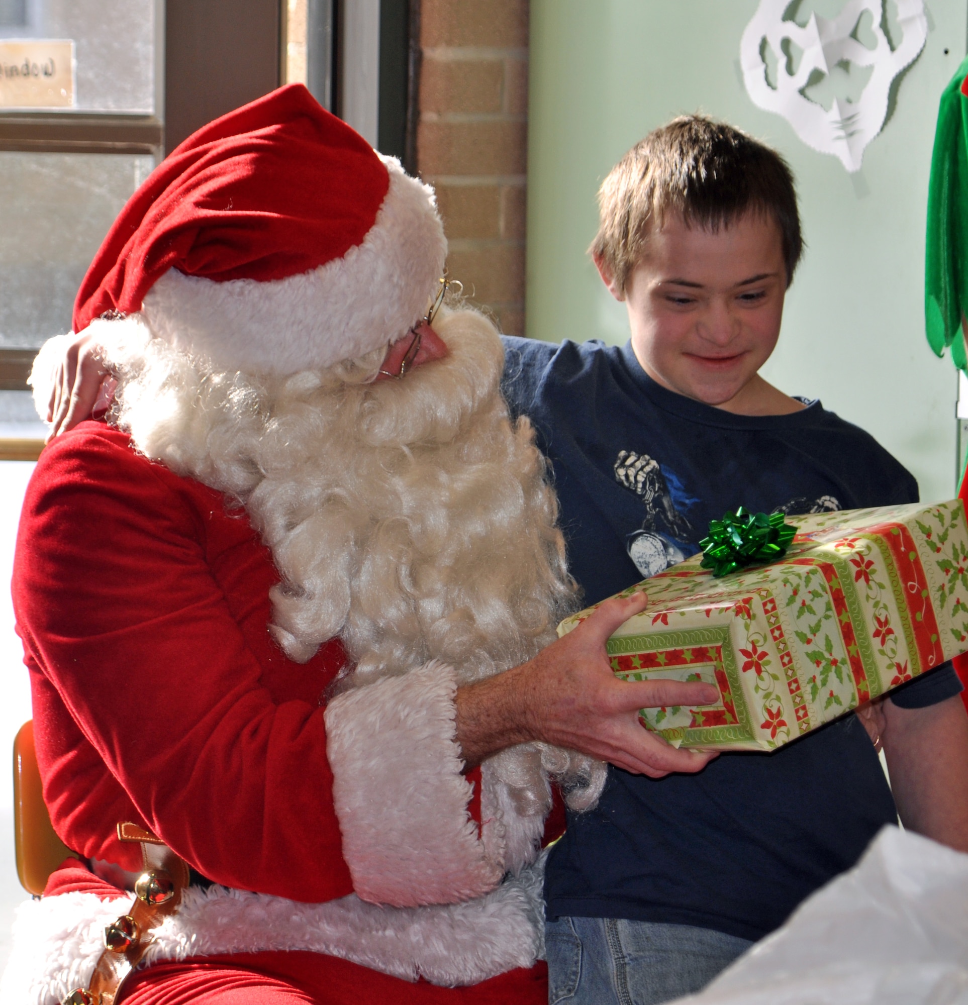 Santa, played by Chief Master Sgt. David Sill, 67th Aerial Port Squadron, hands a gift to Tyler Chapman, a special needs student at Mound Fort Junior High School in Ogden. The 67th APS has organized the party each year since 1990, which includes presents, candy, and a special appearance by Santa. (U.S. Air Force photo/Bryan Magaña)