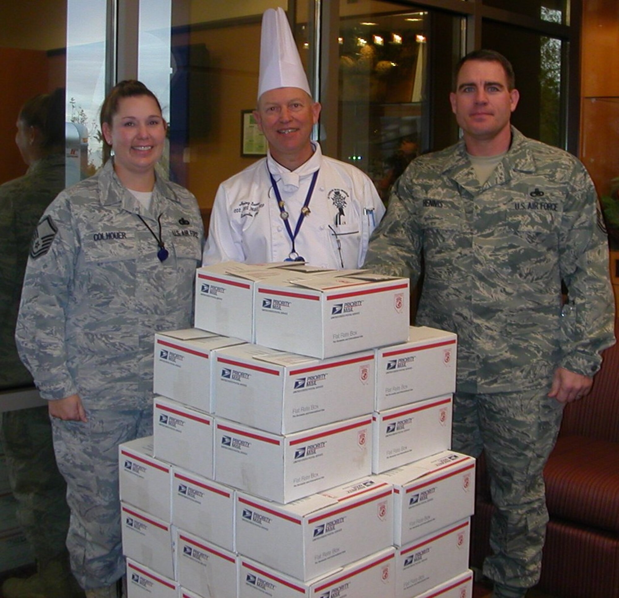 Master Sgts. R. L. Colhouer and William Hennis from the 98th Range Wing accept 5,000 cookies from Heinz Lauer, Head Chef in Charge of the Le Cordon Bleu College of Culinary Arts Las Vegas and honorary commander of the 98th Operations Support Squadron. Mr. Lauer and his staff baked the cookies for Airmen deployed from Nellis and Creech Air Force Bases.(courtesy photo)