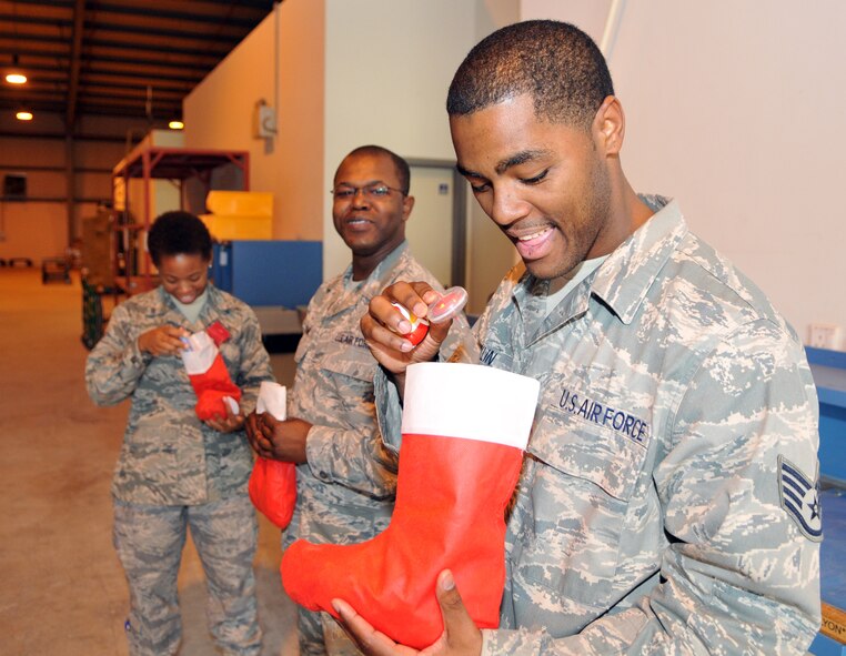 SOUTHWEST ASIA -- Staff Sgt. Brad Ficklin, deployed from the 100th Logistics Readiness Squadron, opens a stocking full of gifts delivered by Col. Chad Manske, 100th Air Refueling Wing commander and Chaplain (Lt. Col.) Frederick Viccellio, during a visit Dec. 18.  (U.S. Air Force photo/Staff Sgt. Austin M. May)